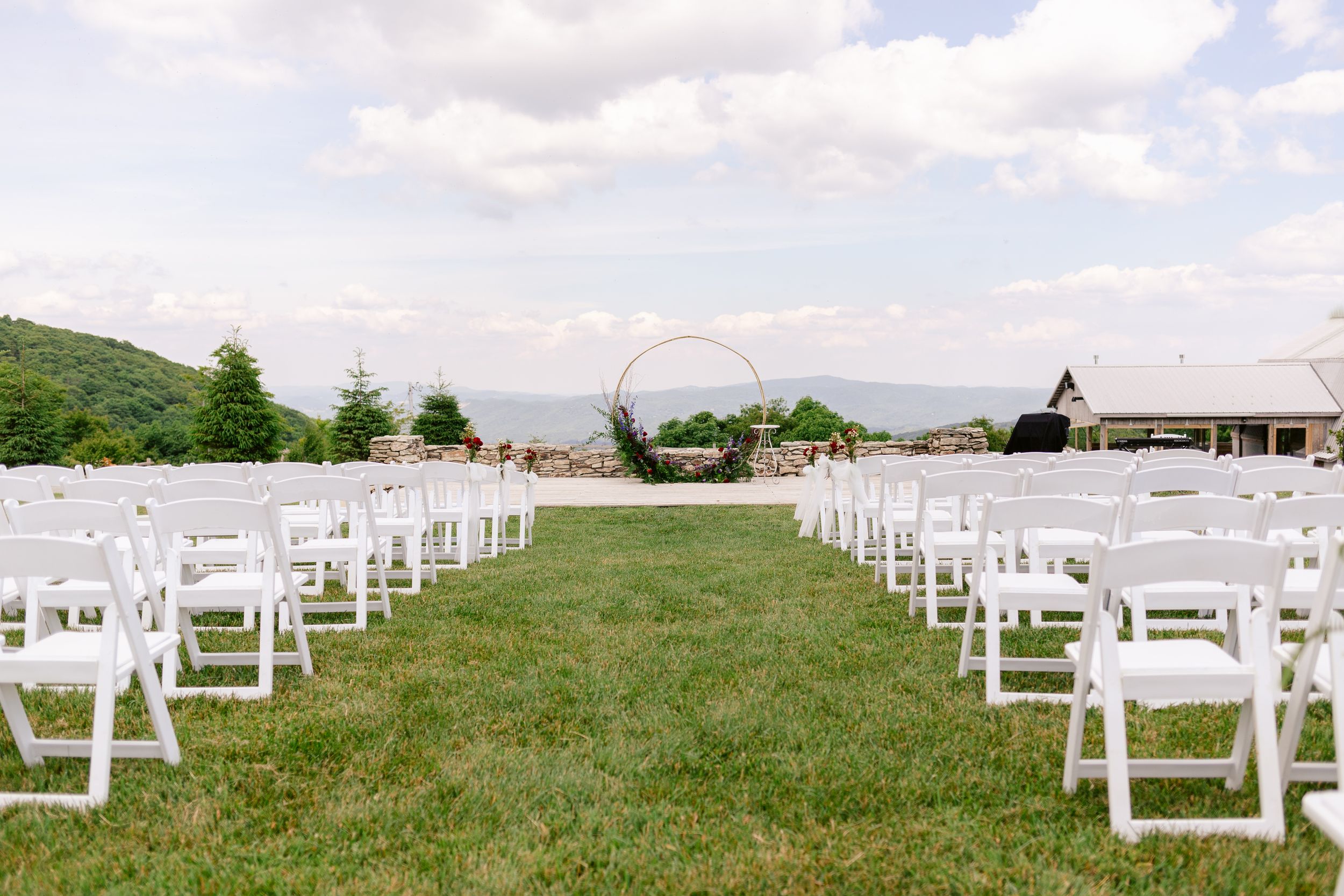 Rows of white chairs set up for an outdoor wedding ceremony with mountain views.