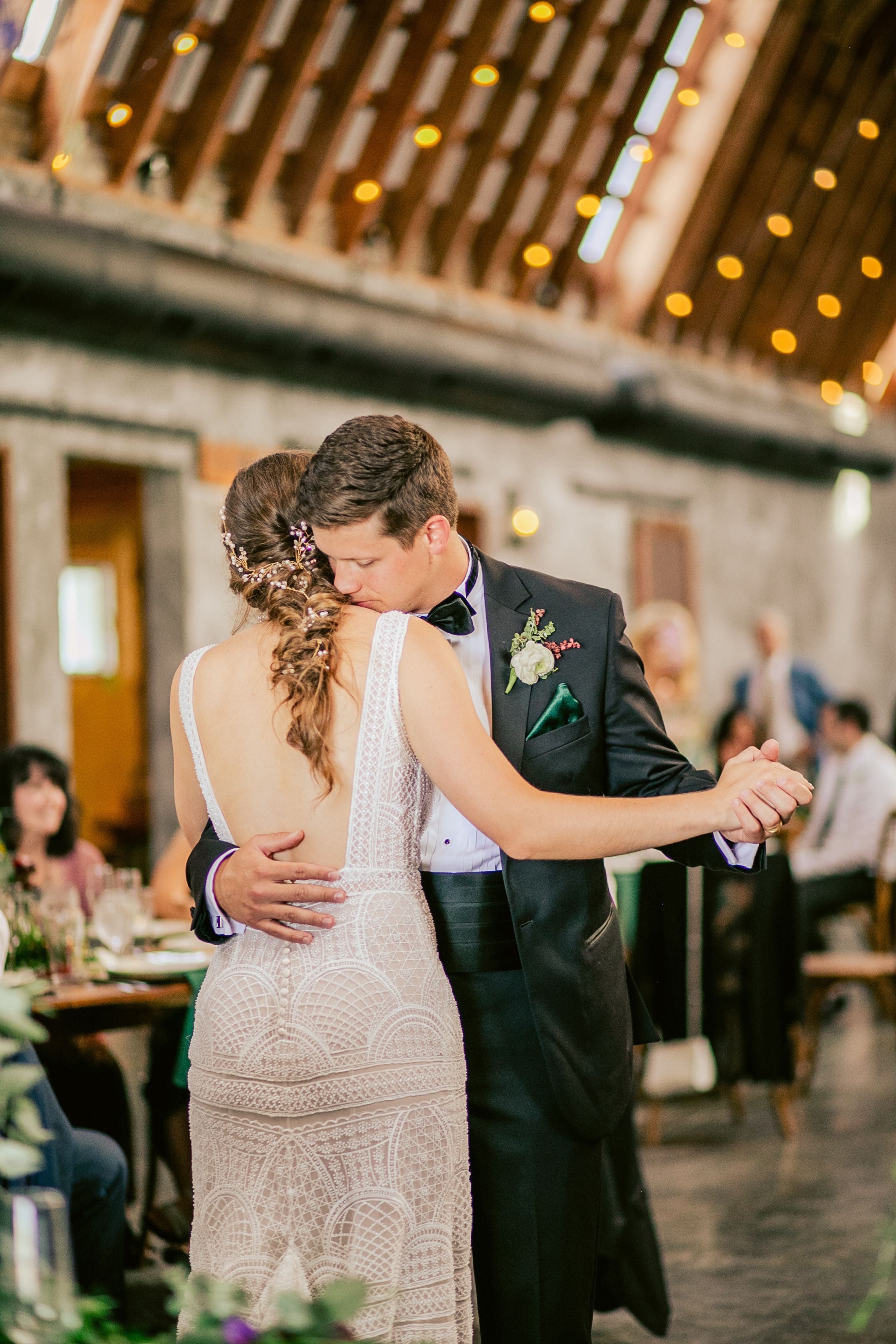 A couple in formal attire sharing a romantic slow dance at their wedding reception.