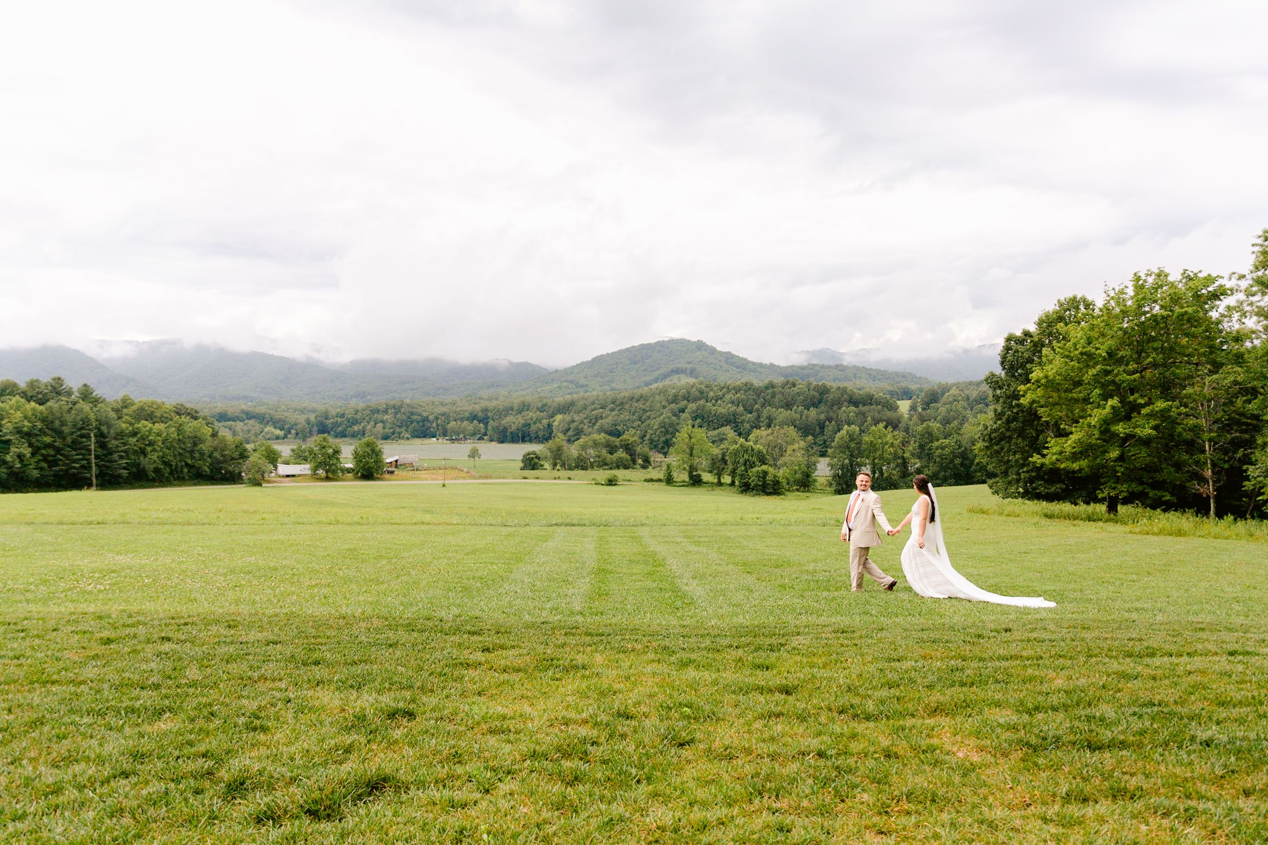 Panoramic view of rolling green hills and mountains under cloudy skies.