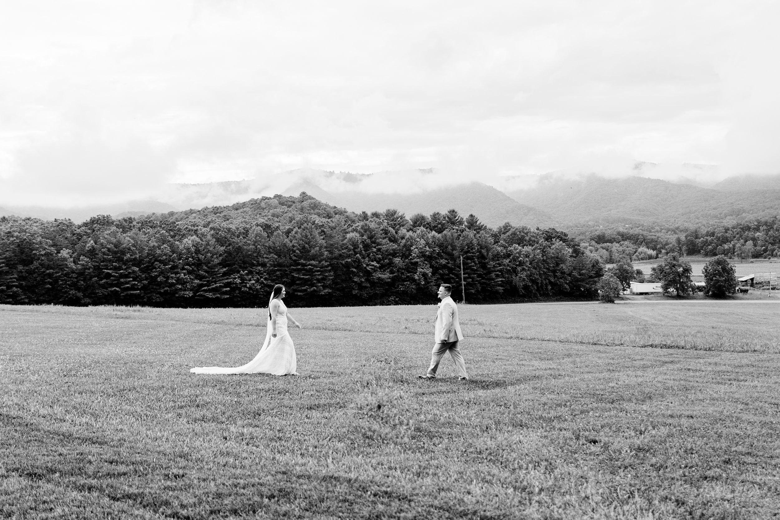 Two figures walking across an open field with mountain views in black and white photography.