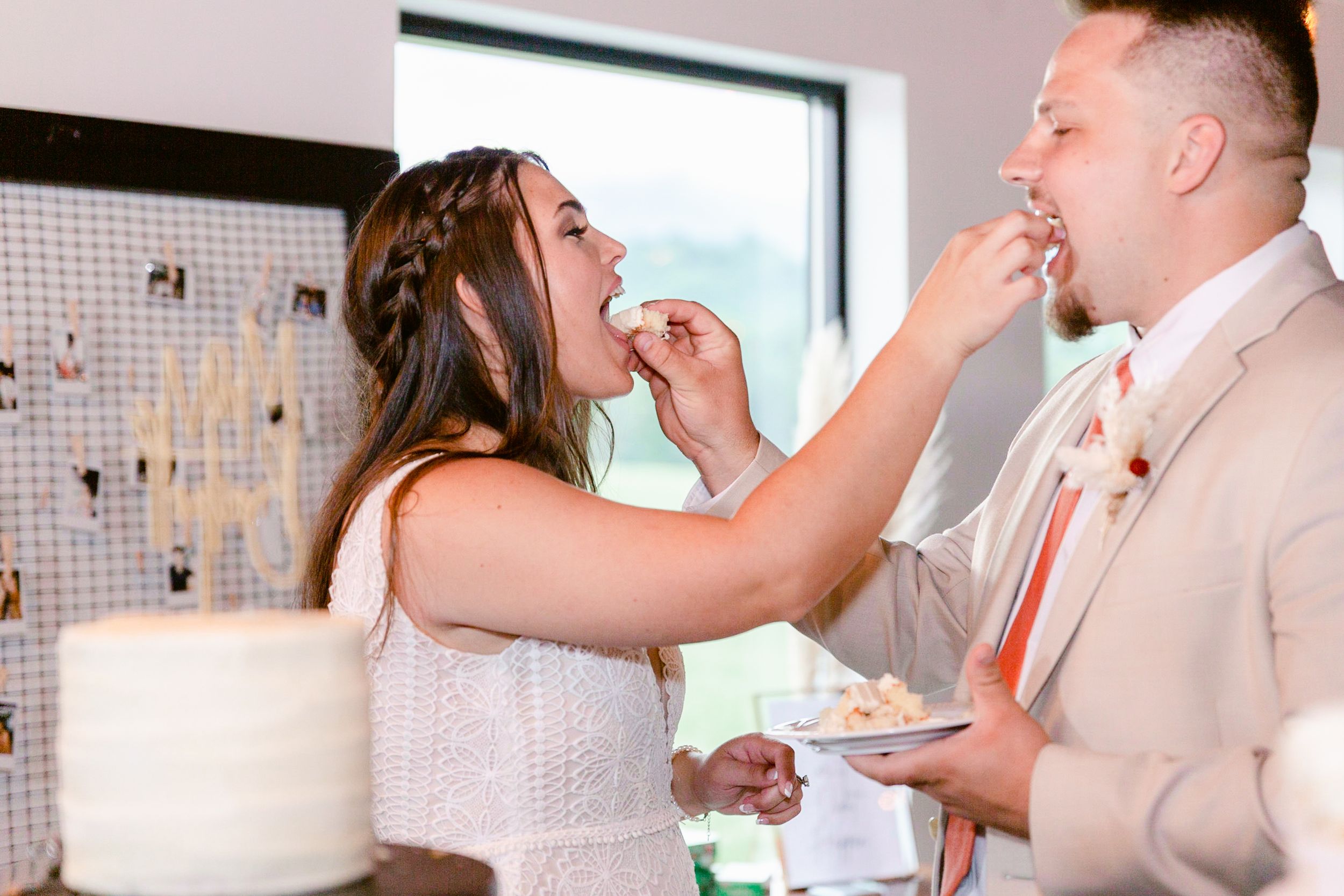 Wedding couple dancing in a bright reception space with white decor and natural lighting.