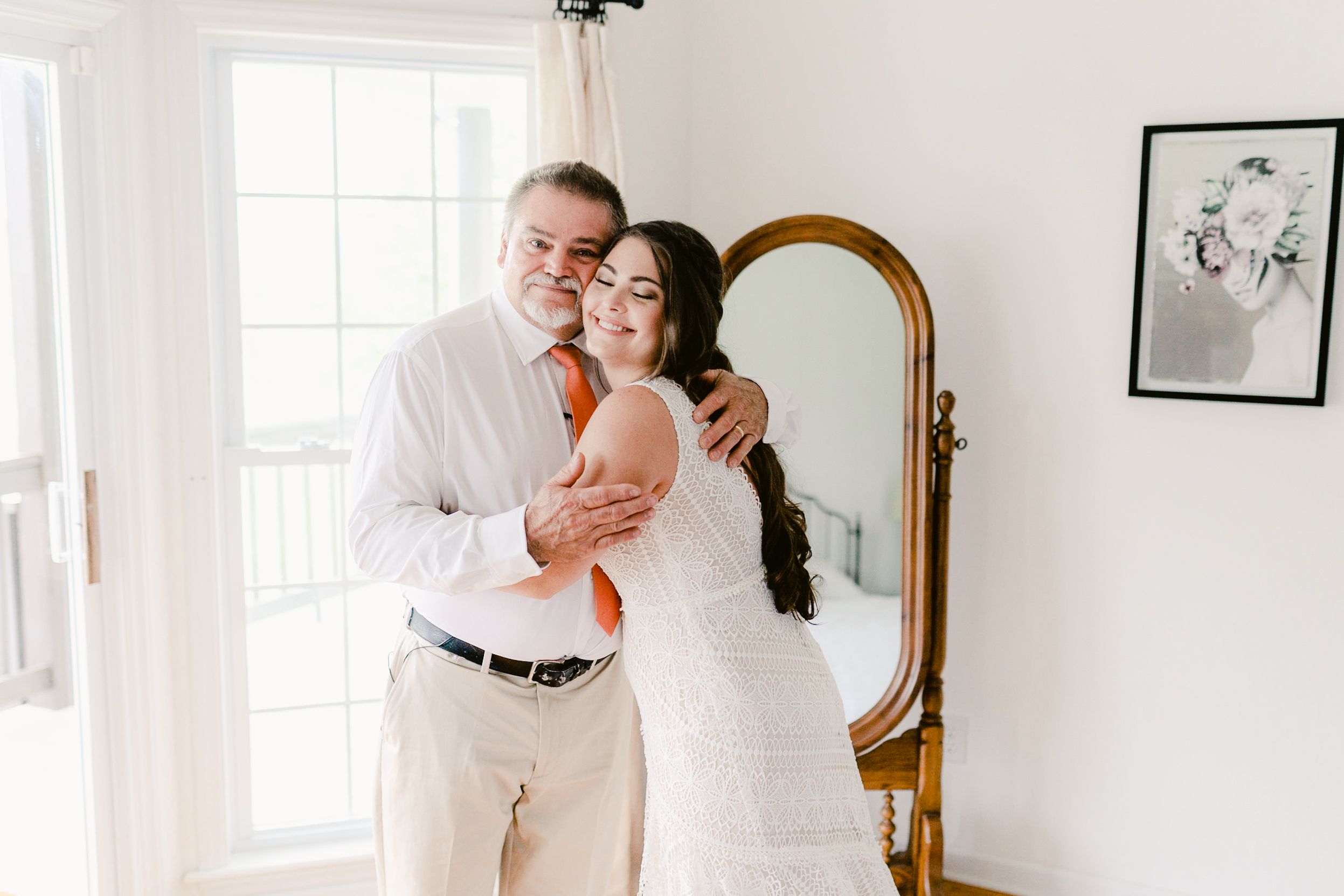 A tender moment shared between two people in formal attire next to an elegant gold-framed mirror.