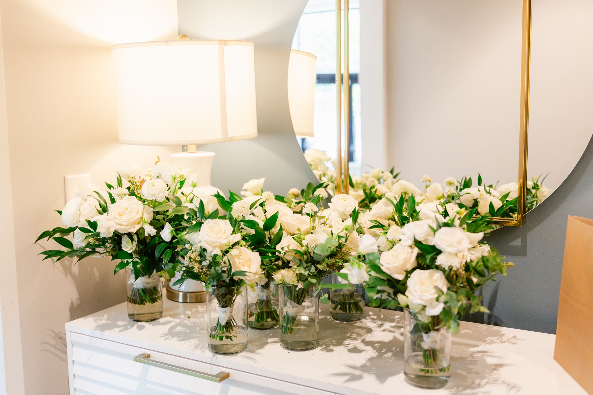 A long banquet table decorated with elegant white floral centerpieces and gold candlesticks in a bright, modern setting.