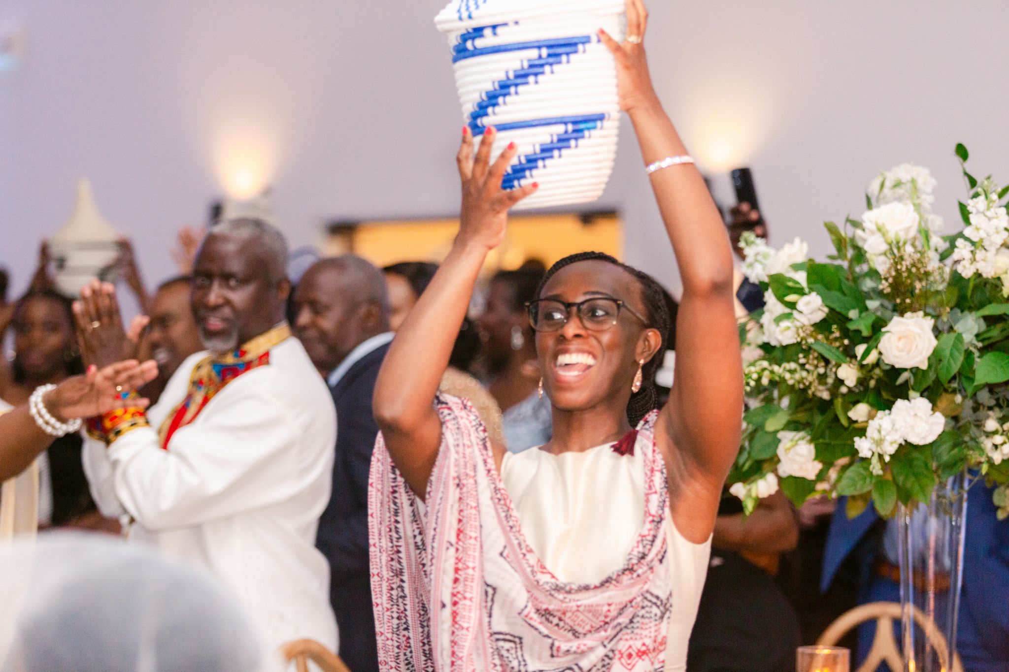 Wedding guests dancing and celebrating with raised arms at a lively reception party.