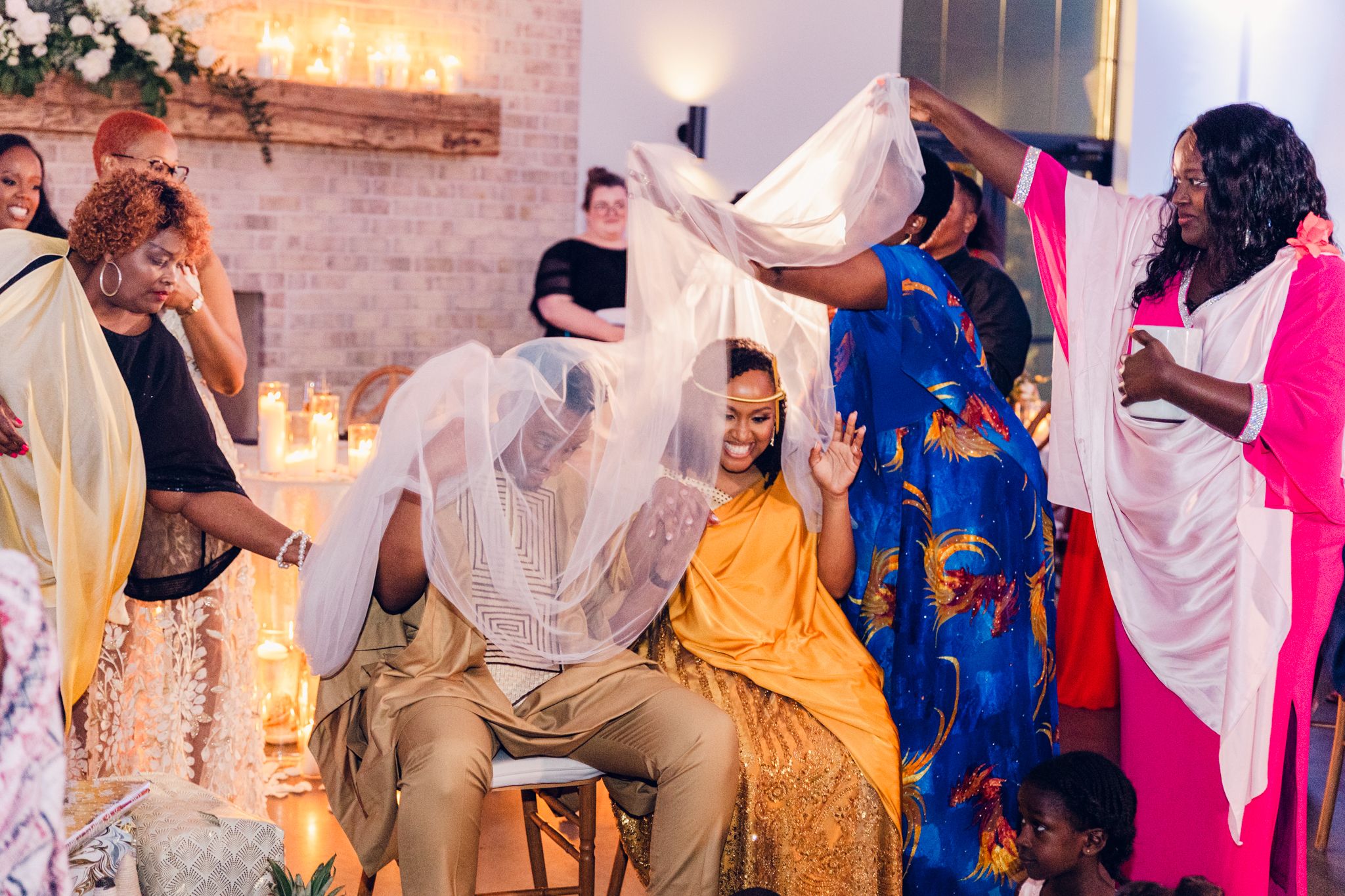 Wedding party members in yellow and blue attire dancing and celebrating at an indoor reception.
