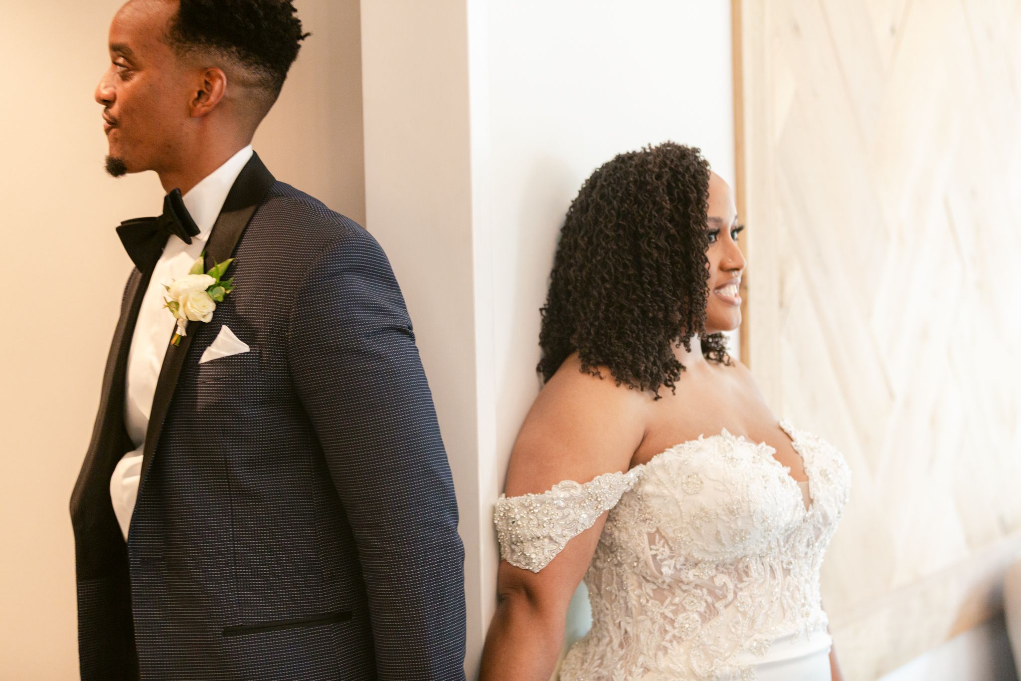 A bride and groom share a private first look moment before their wedding ceremony, separated by a white wall.