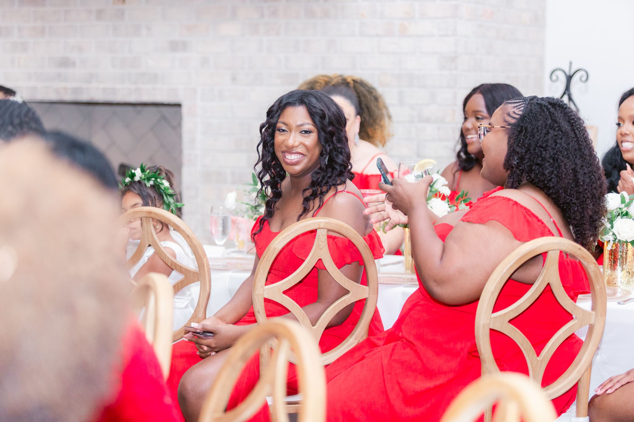 Bridesmaids in red dresses celebrate during wedding reception.