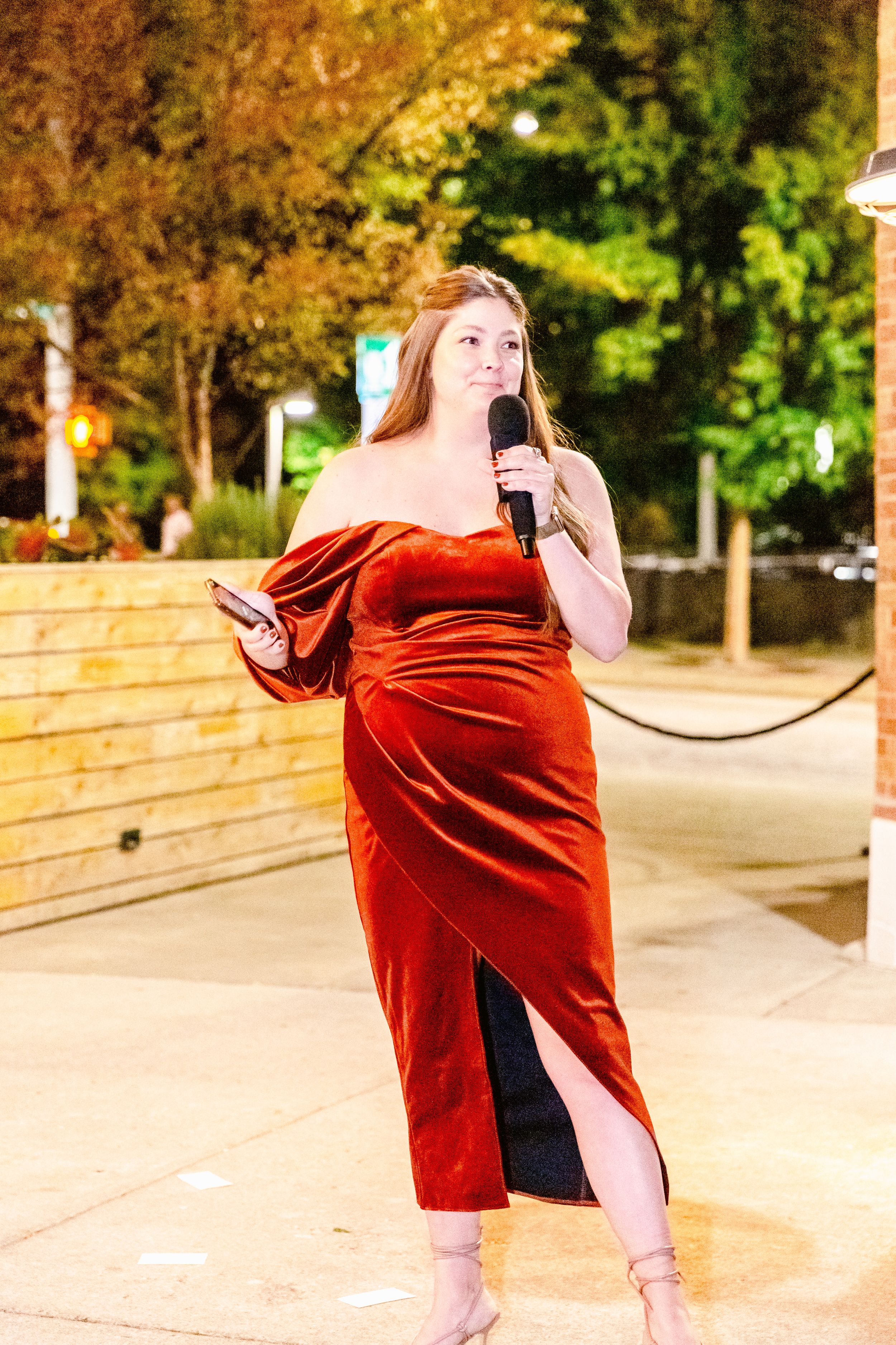 A dancer in a flowing red velvet dress performs an expressive movement sequence outdoors at dusk.