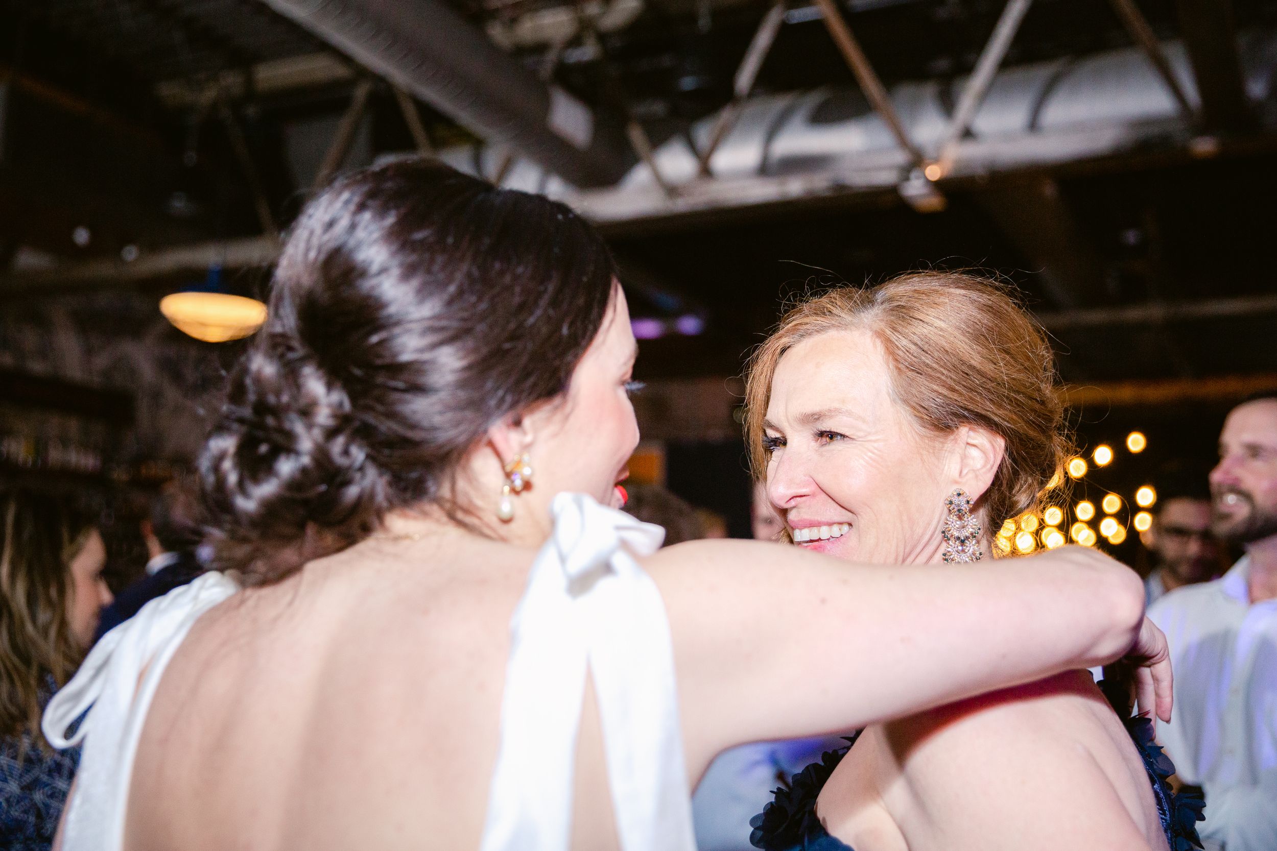 Joyful celebration at a wedding reception with guests dancing under warm lighting.