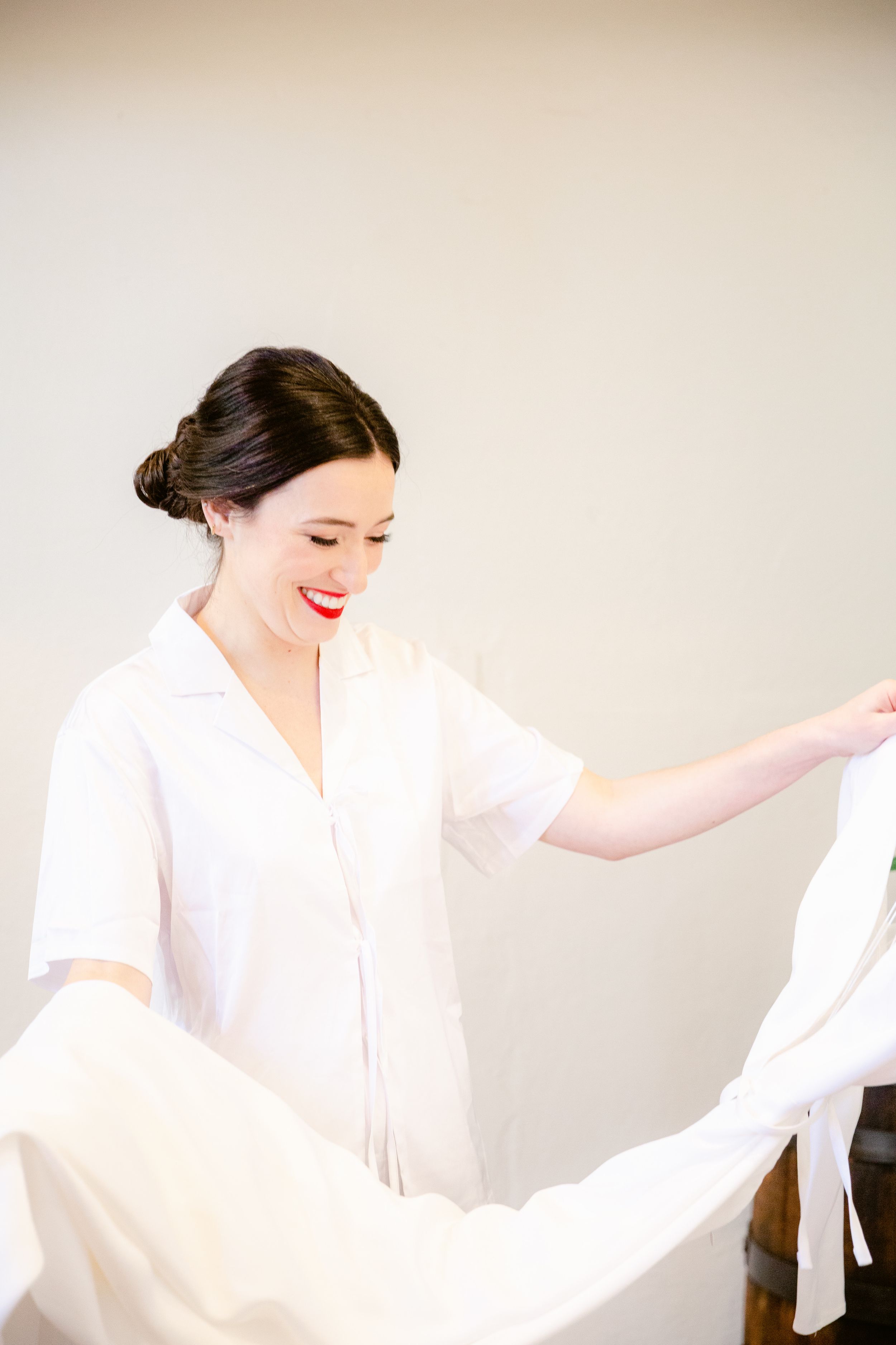 A person in a flowing white dress moves gracefully in a dance-like motion against a neutral background.