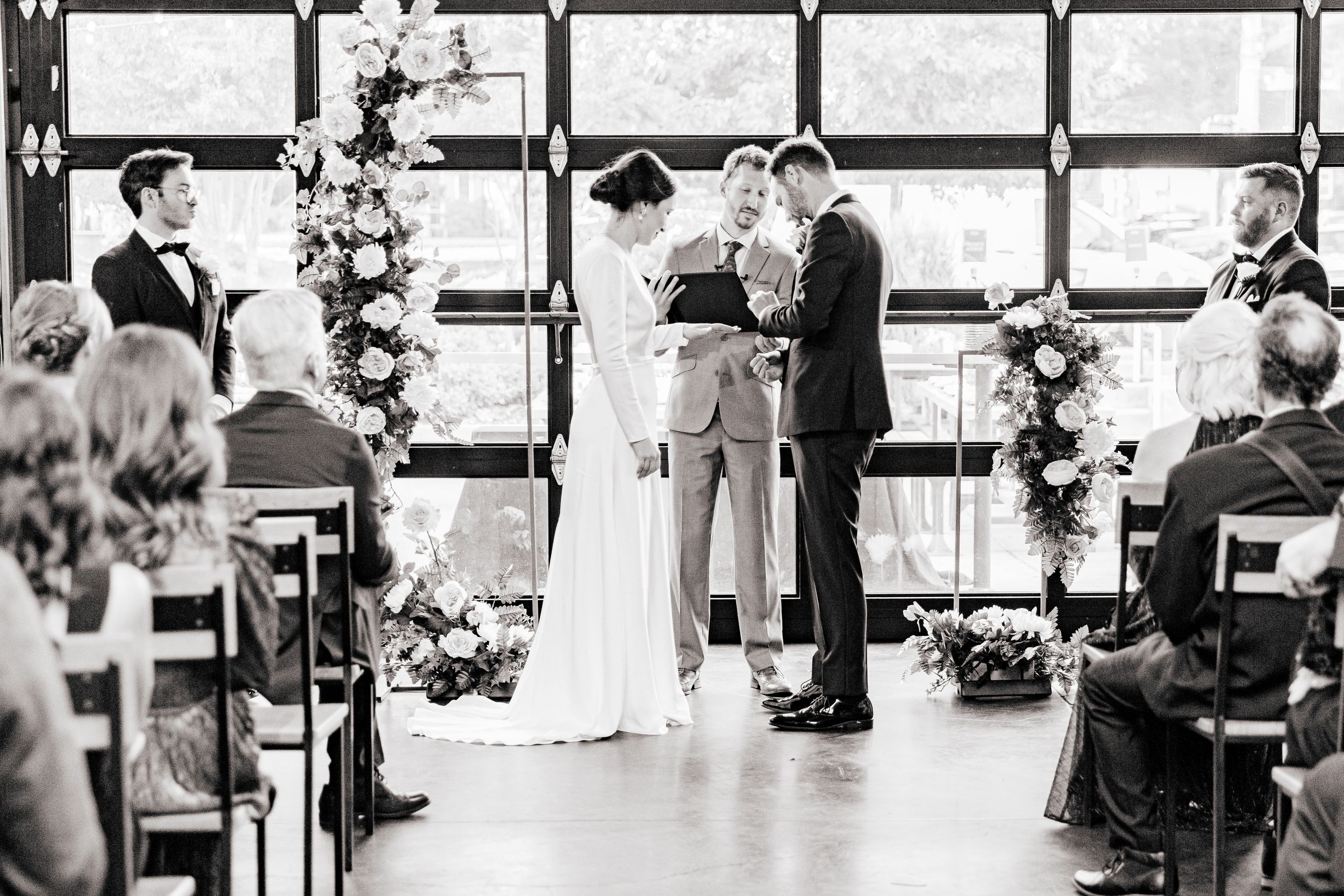 A wedding ceremony in progress with guests seated in rows watching the couple exchange vows at the altar.