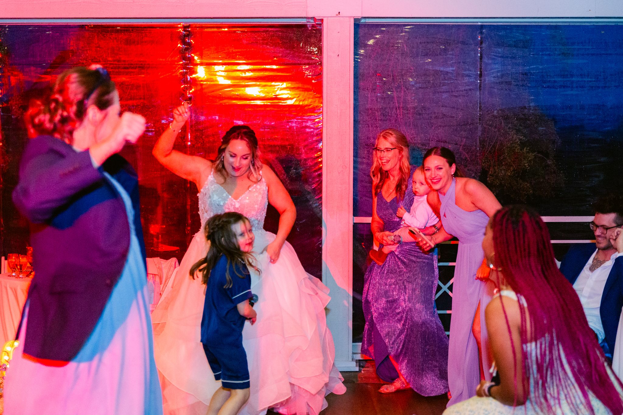 Couples dancing together at a wedding reception with colorful red and blue lighting effects creating a romantic atmosphere.