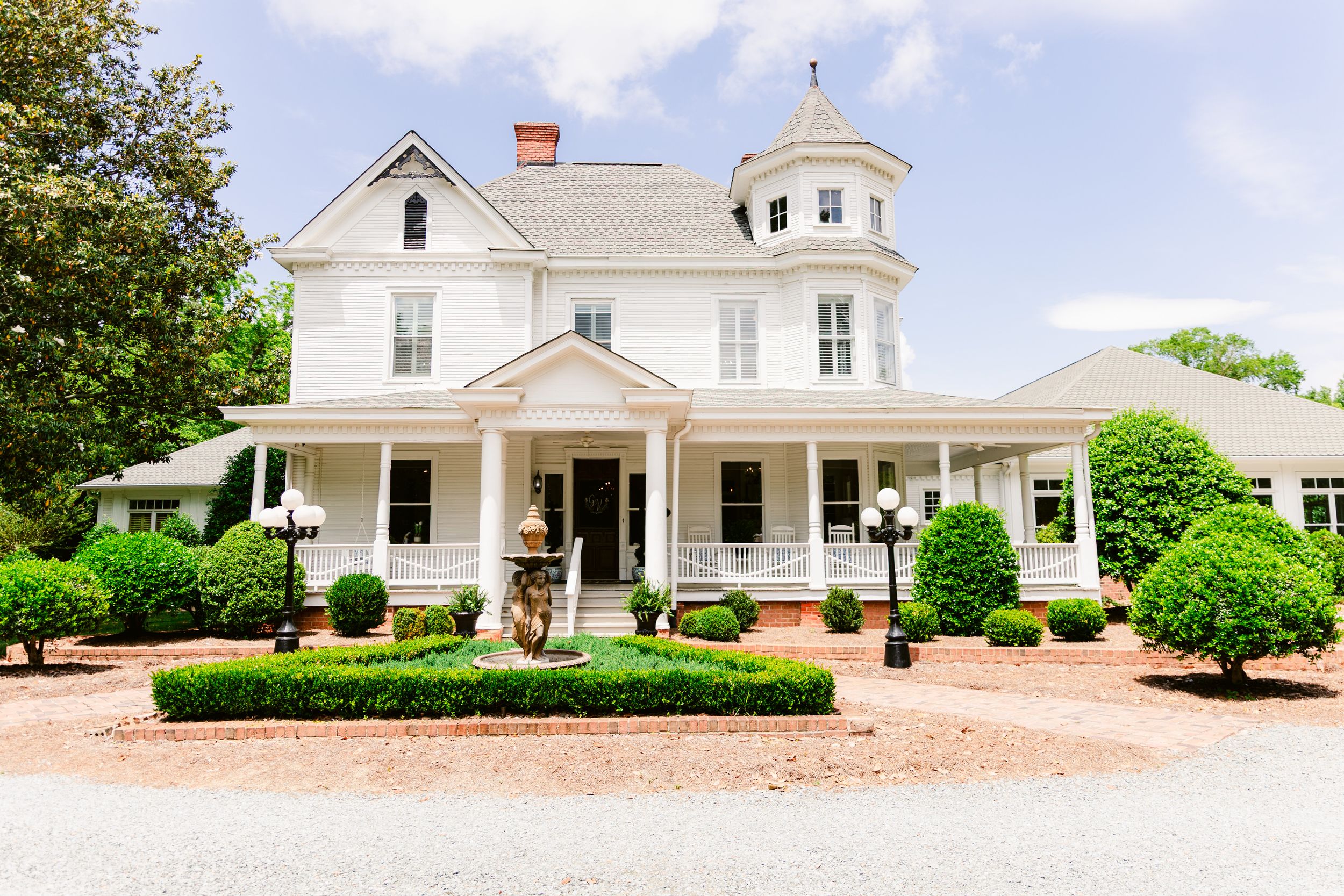 White farmhouse-style building with wraparound porch and cupola shown from multiple angles in panoramic view.