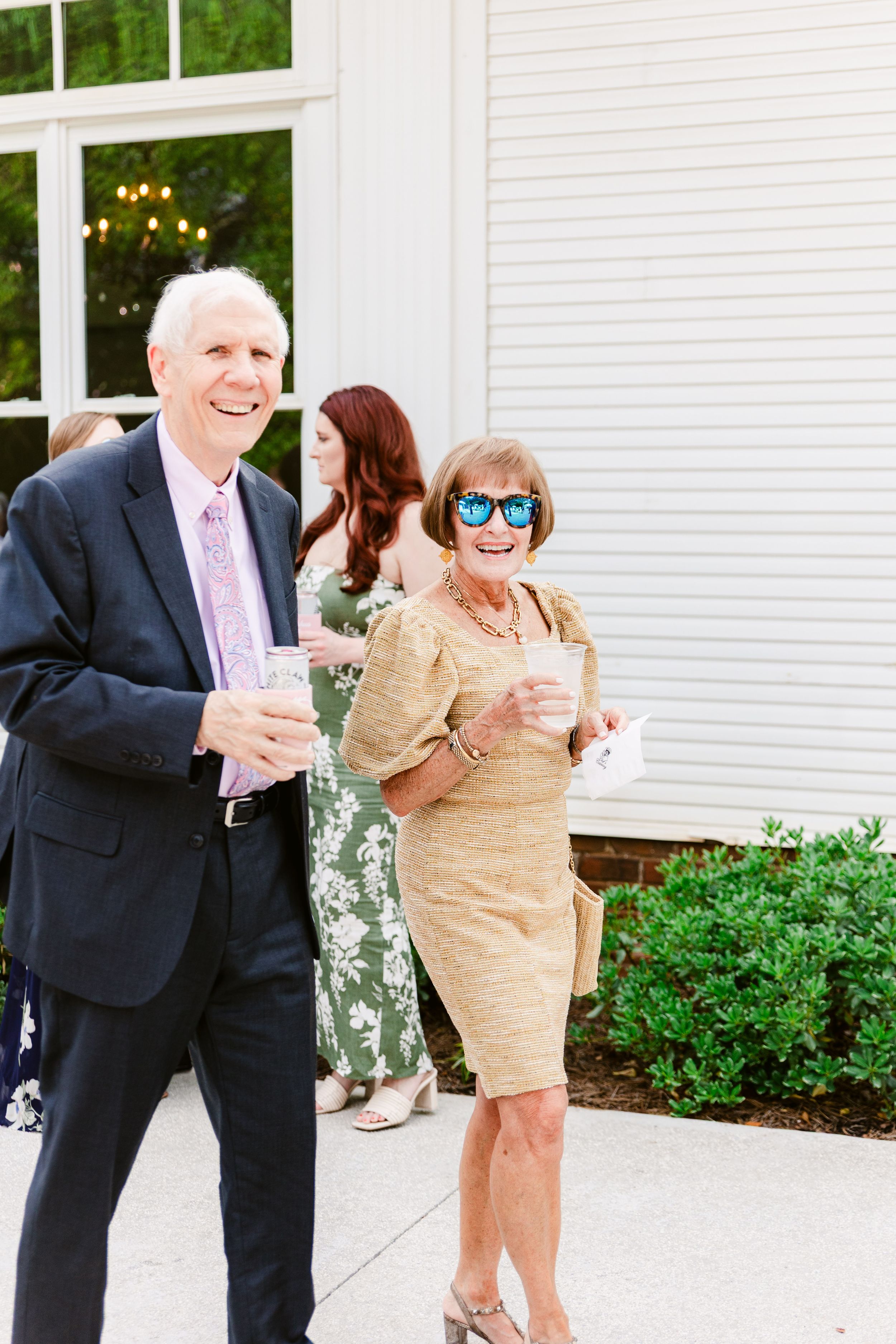 Couples dancing together on a white patio during an outdoor celebration.