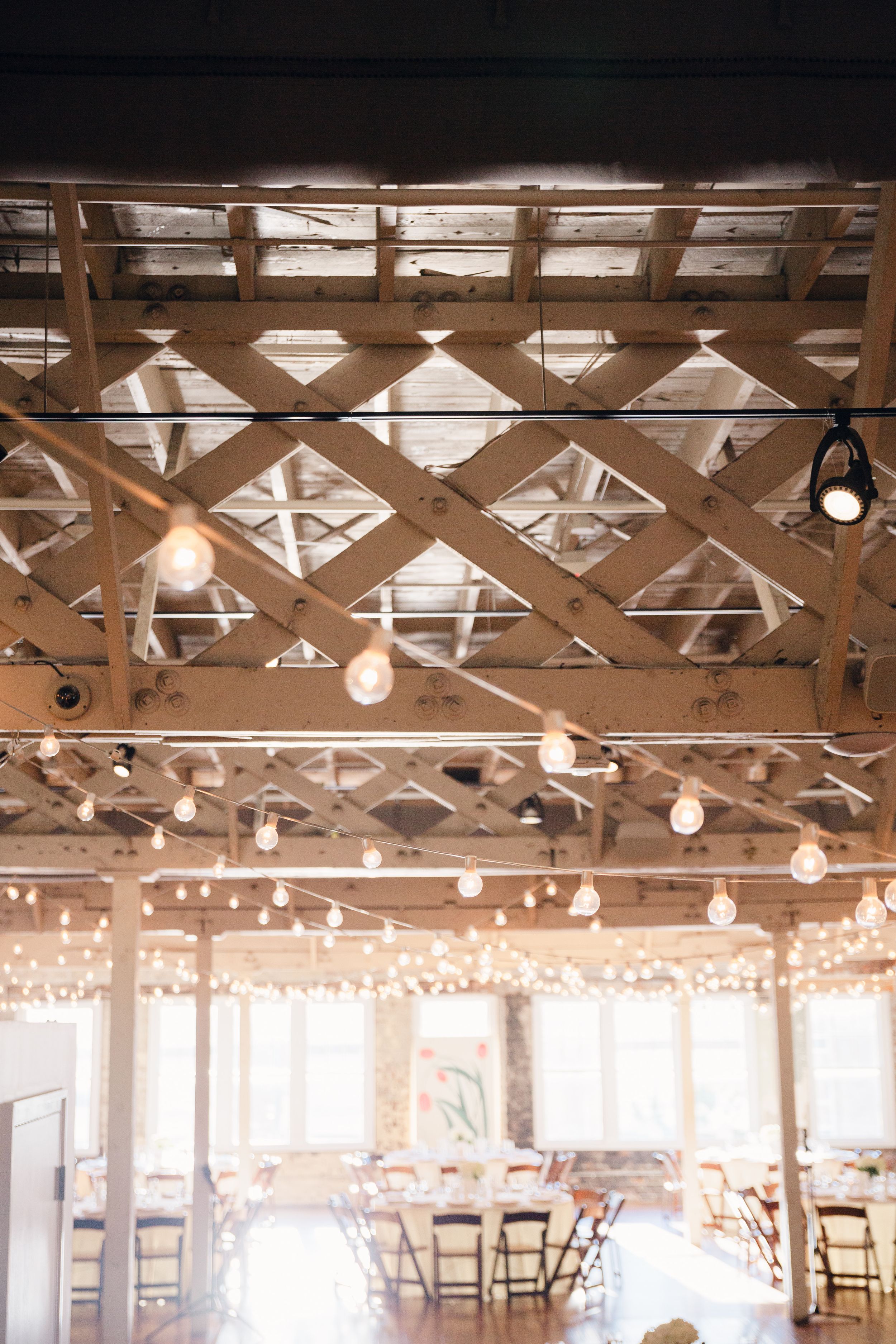 Industrial ceiling with lattice framework and hanging string lights creating romantic ambiance.