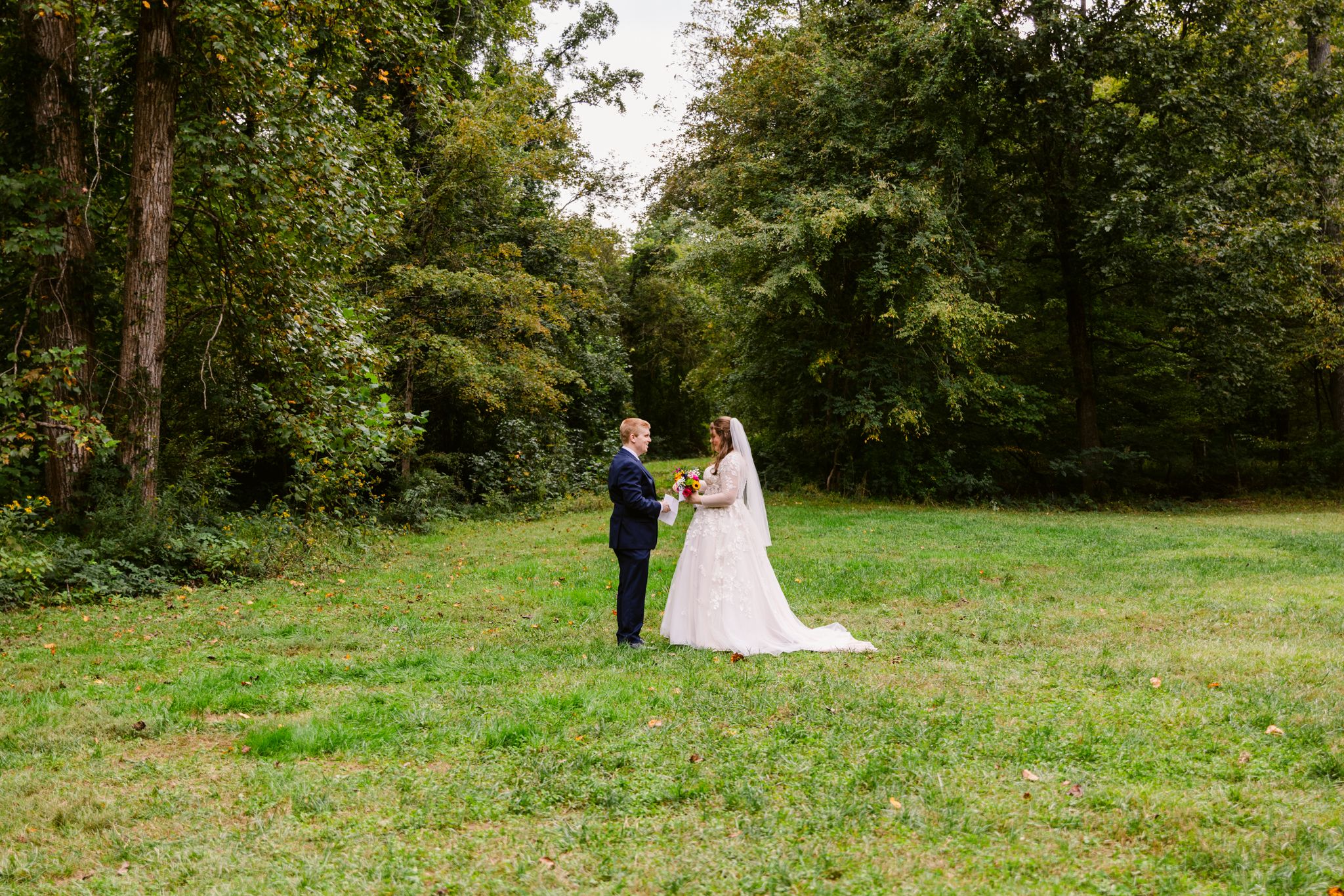 A couple shares a romantic moment in a lush green garden setting during their wedding celebration.