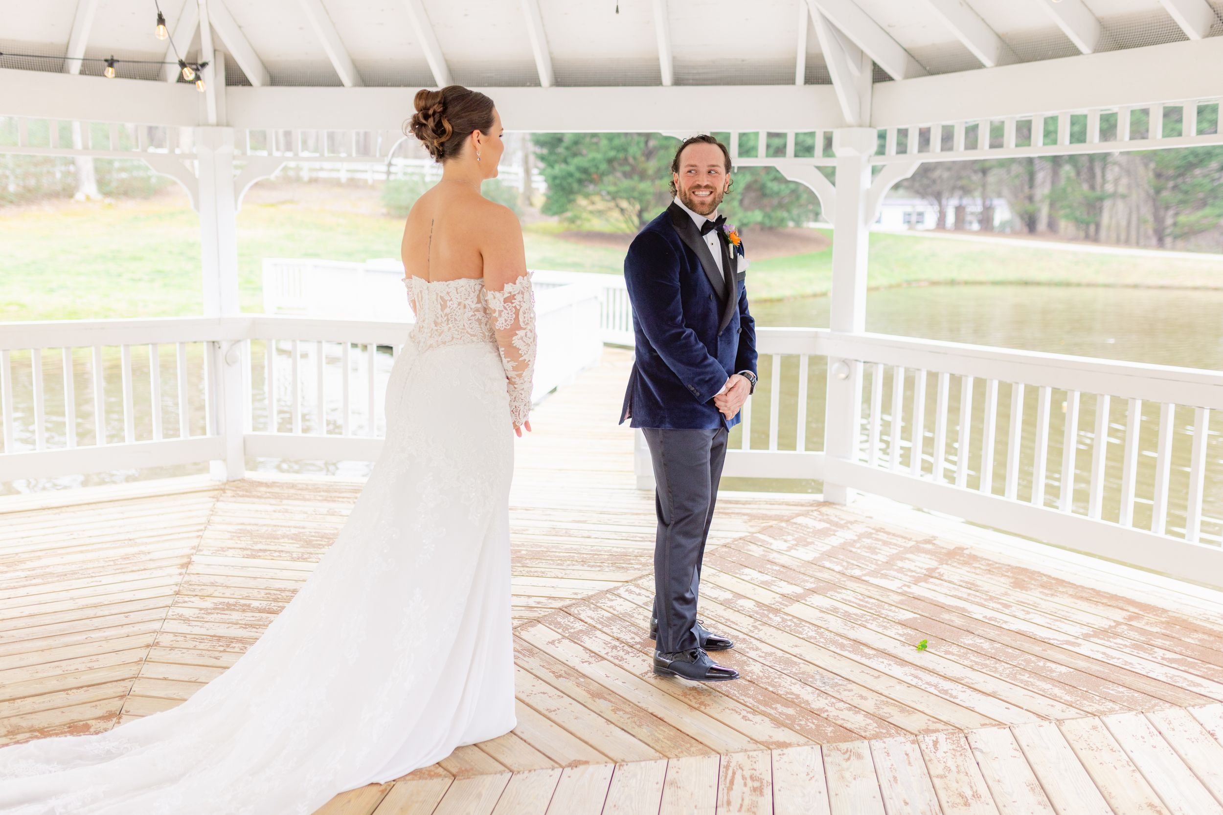 A couple share their first look moment under a white gazebo during their wedding day.