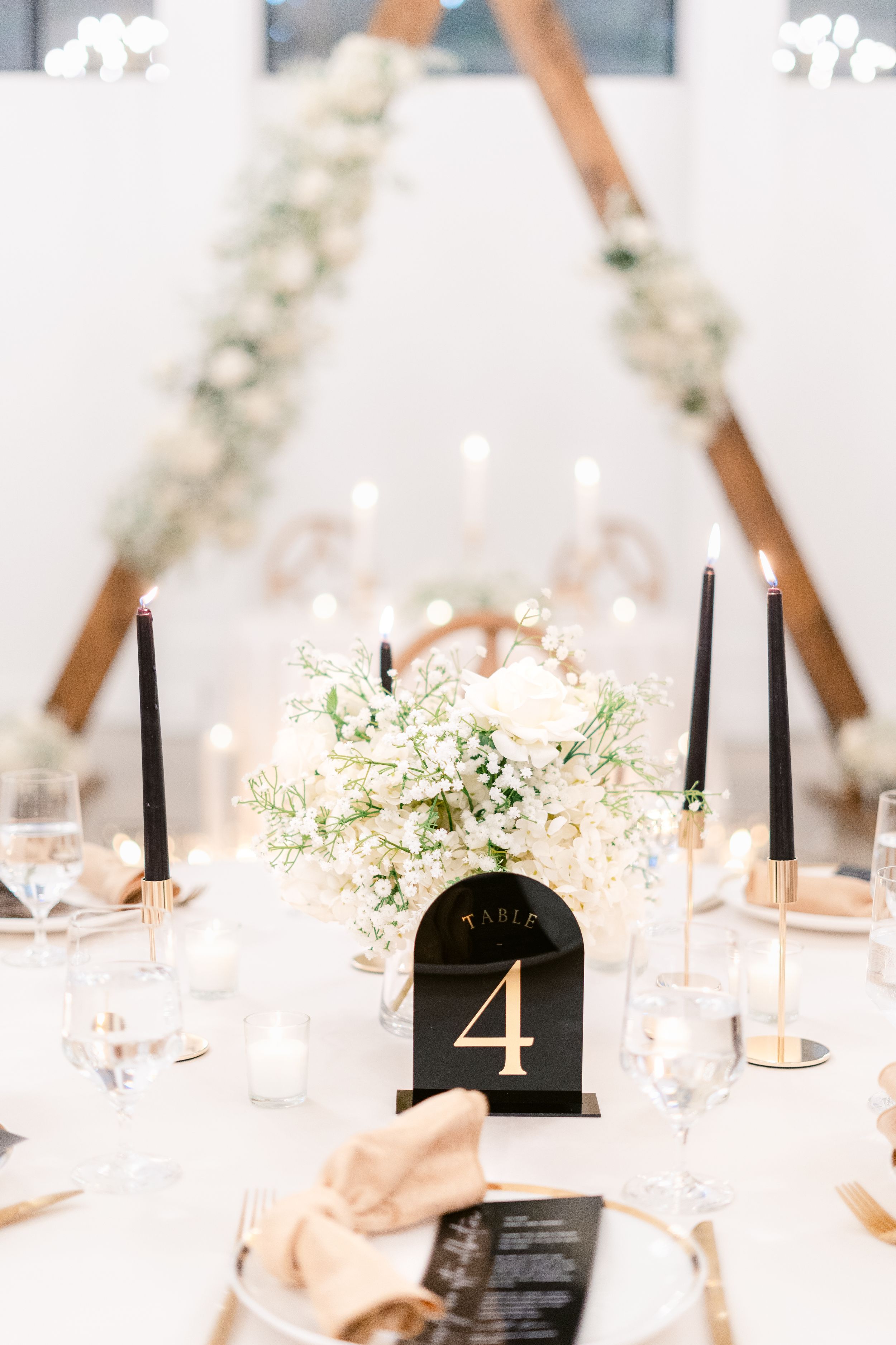 Wedding reception tables with white floral centerpieces and black table numbers.