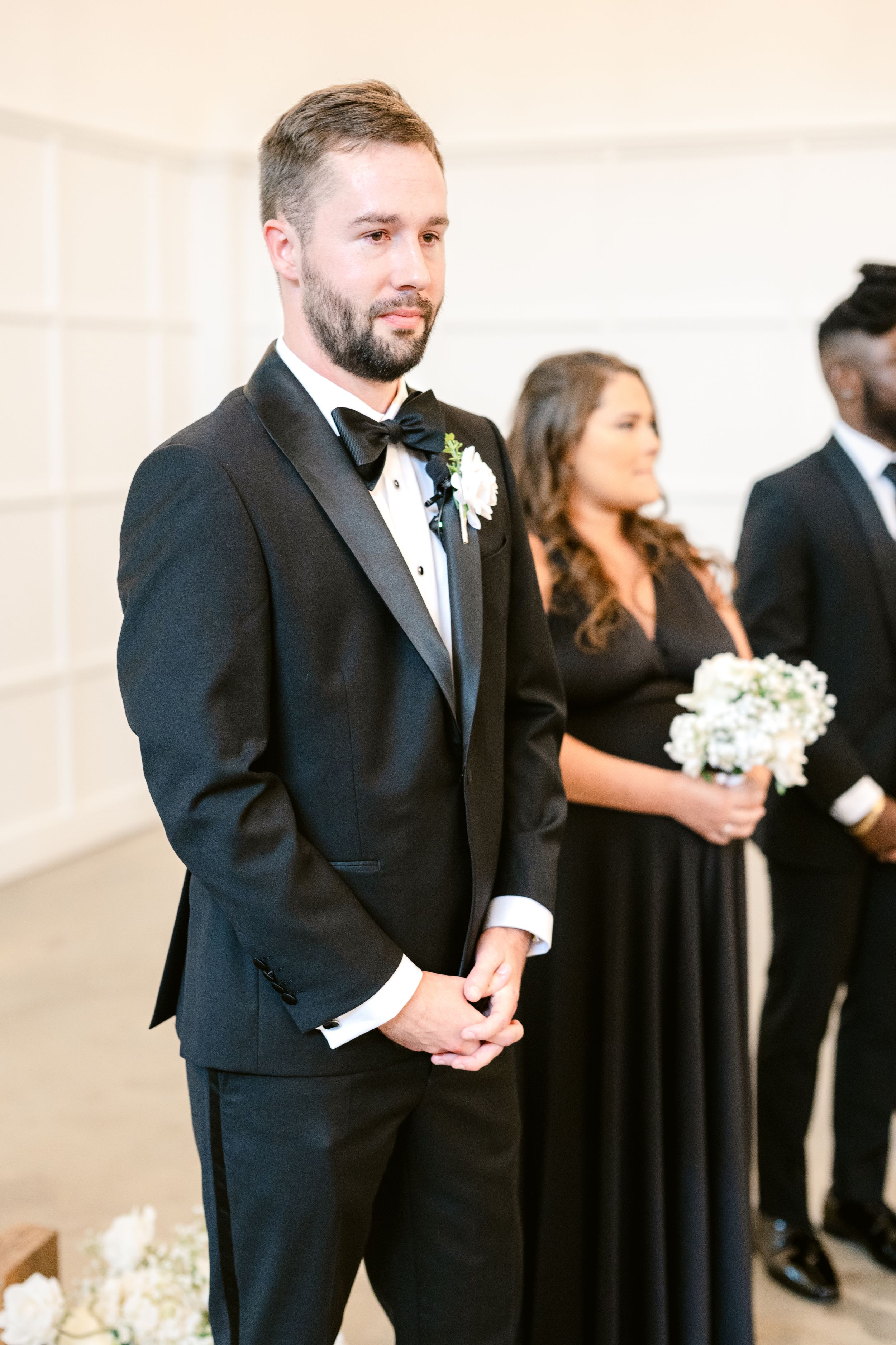 Wedding party members in formal black attire walk together during a ceremony procession.