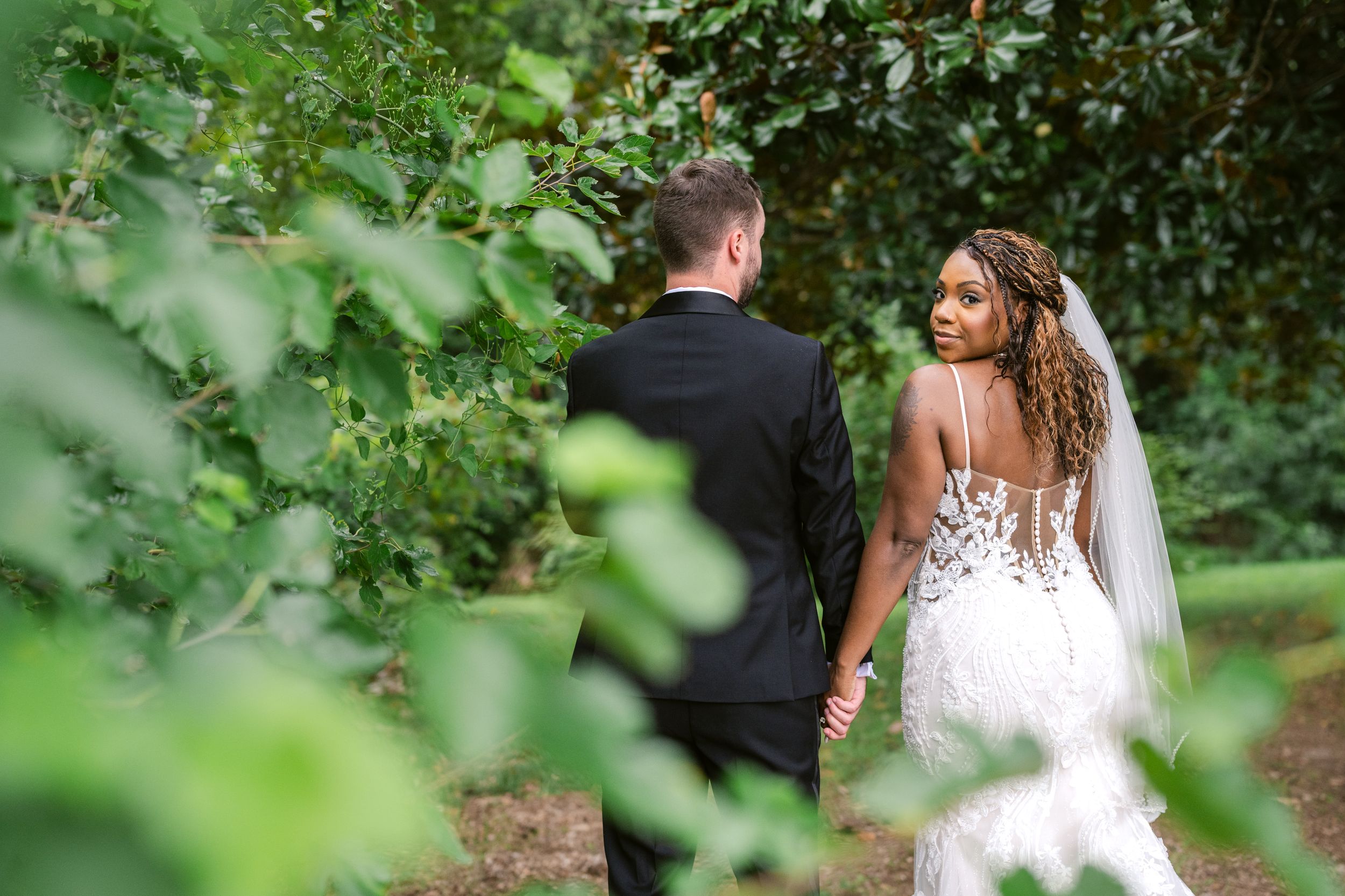 A beautiful wedding scene with a flowing white lace dress against a backdrop of green foliage.