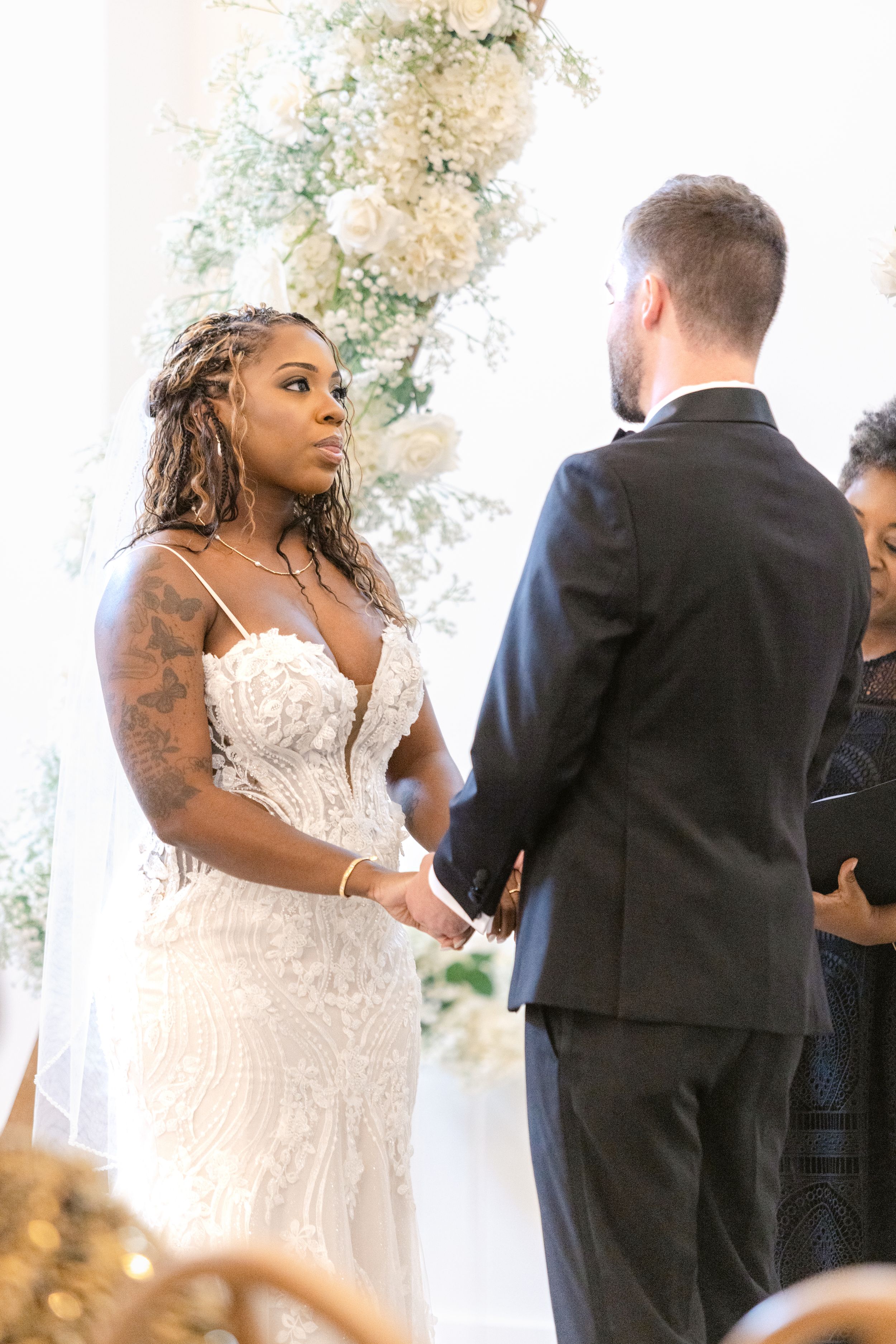 A couple exchanges vows during an intimate wedding ceremony under natural light indoors.