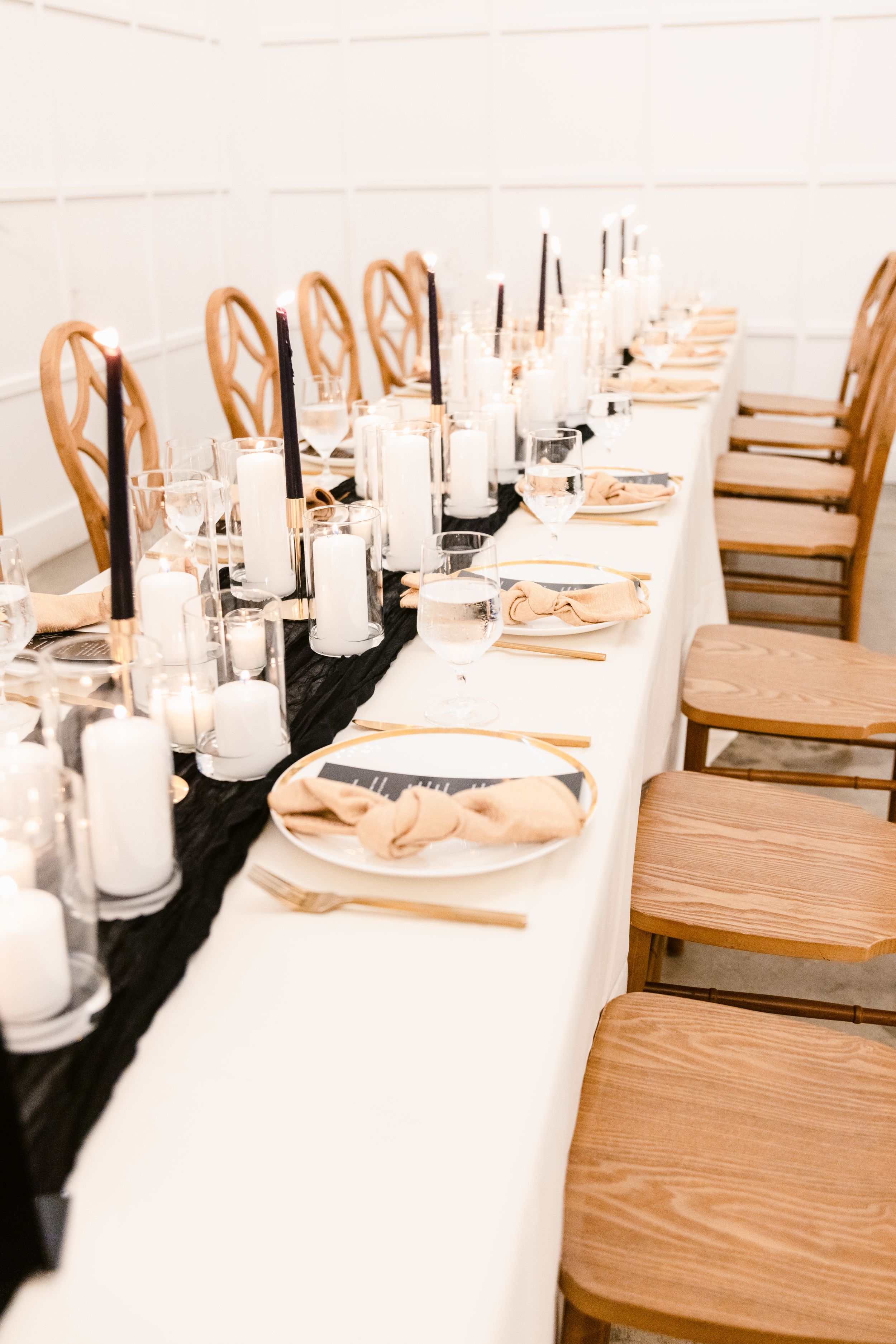Elegant table settings with white linens and wooden chairs at a formal event.