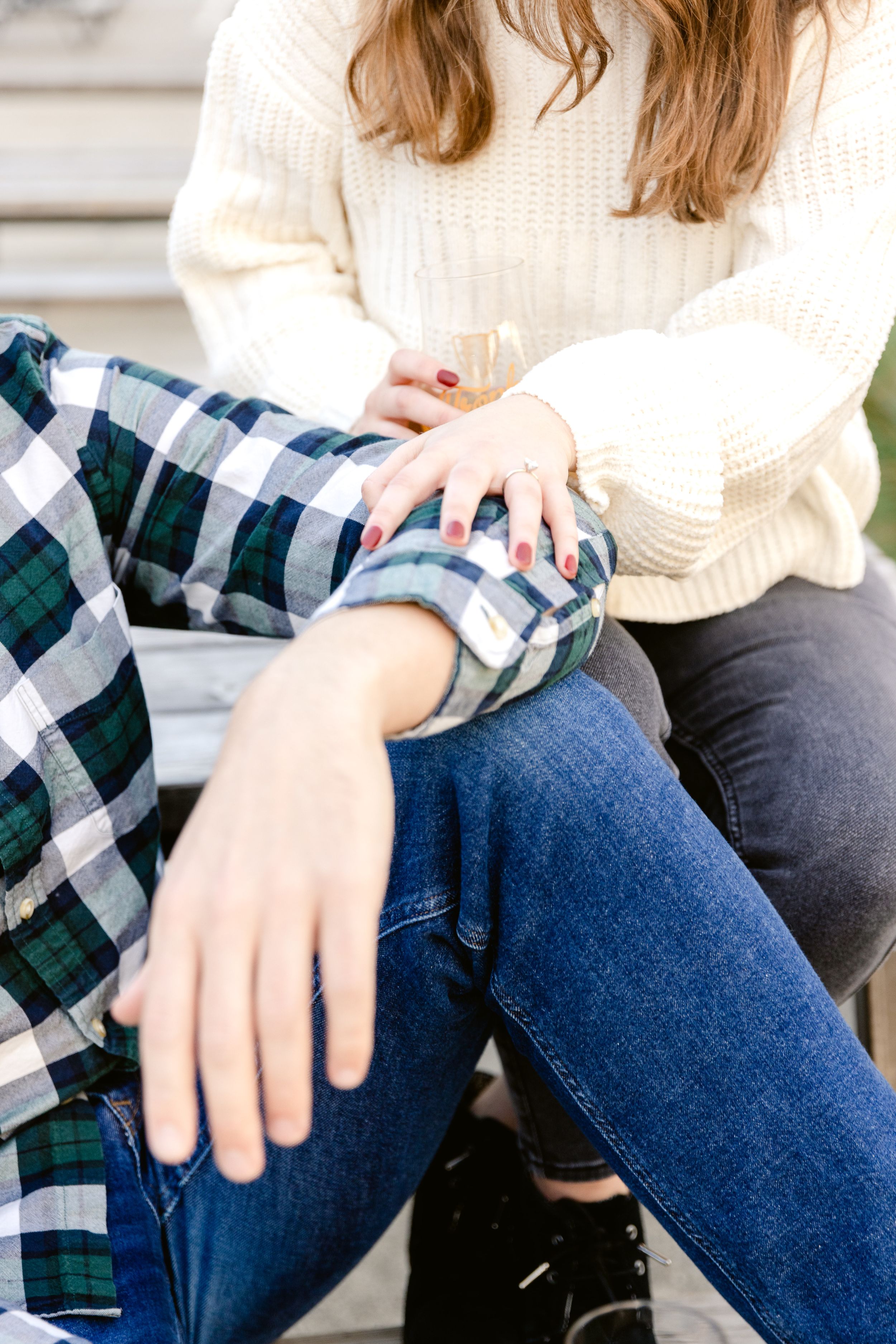 Close up of two people sitting together wearing coordinating plaid and knit sweaters in blue and cream.