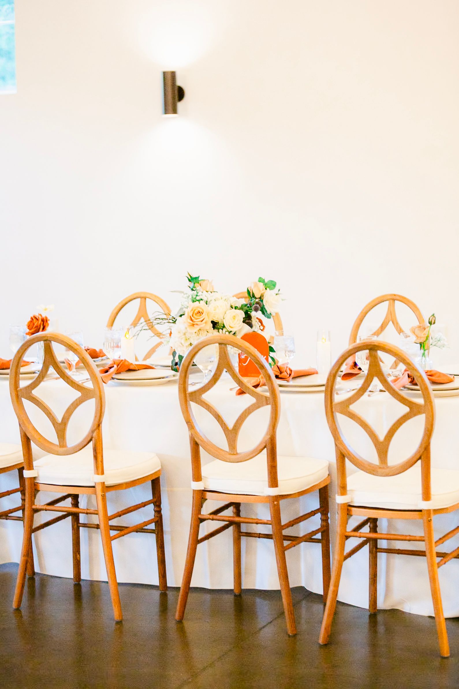 Elegant wooden chairs with geometric backs arranged at a dining table with floral centerpieces.