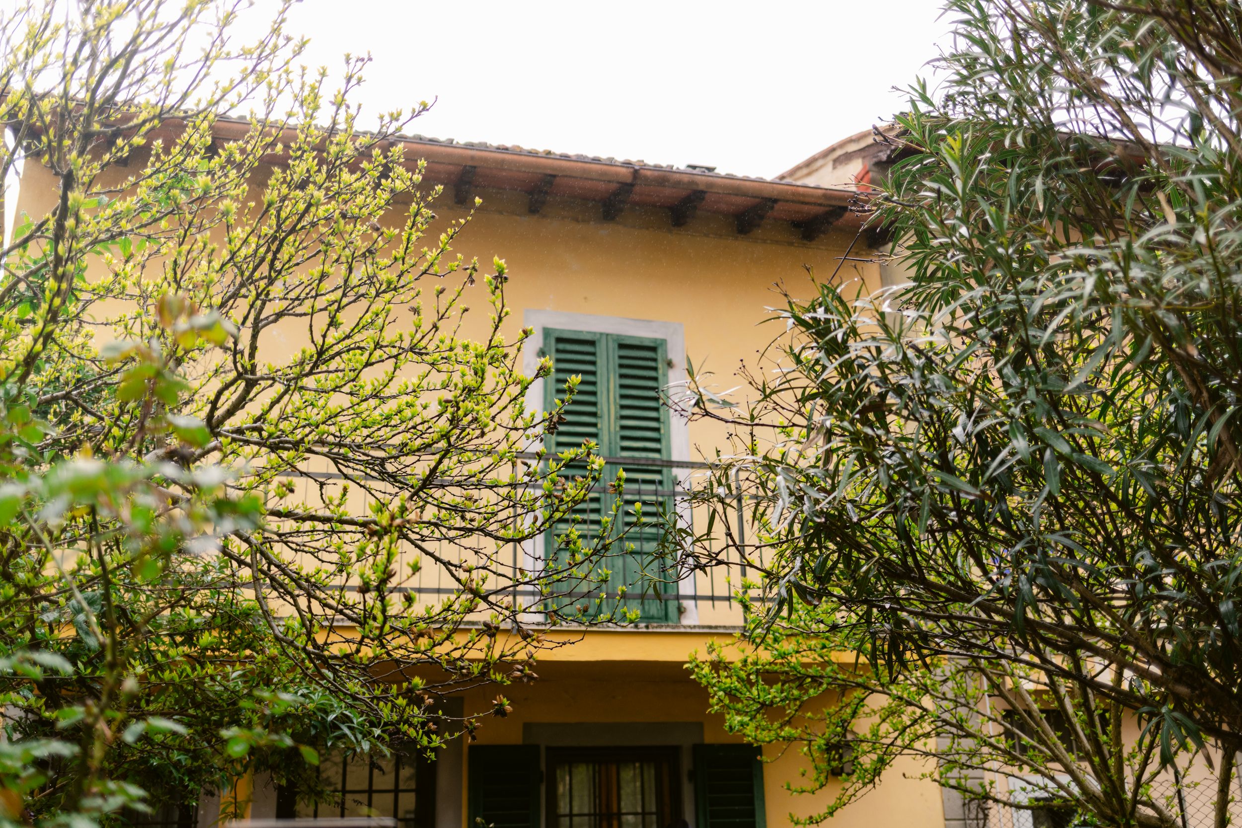 Mediterranean style houses with green shutters and terracotta roofs under cloudy skies.