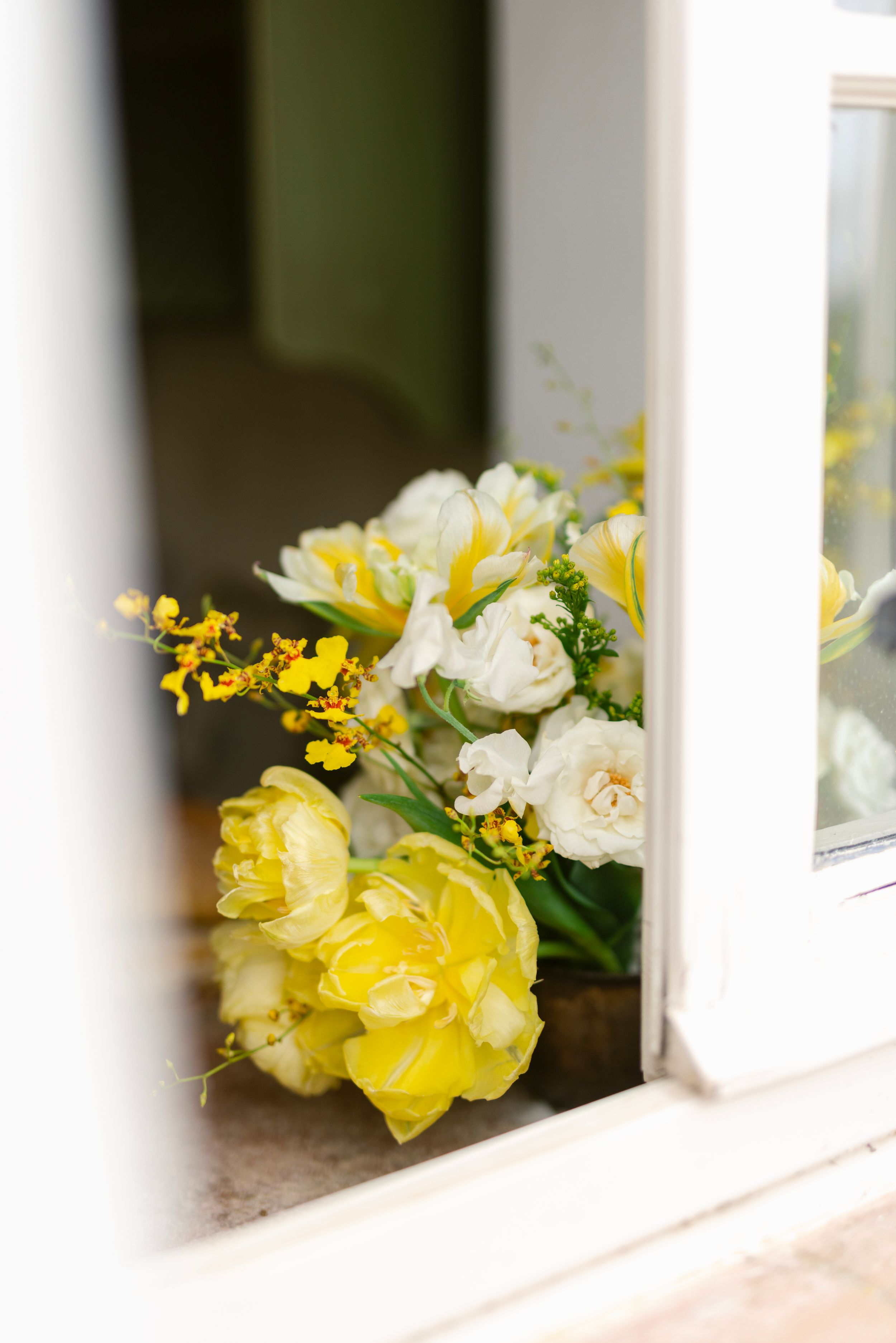 Yellow and white flowers arranged between white porch railings create a charming decorative accent.