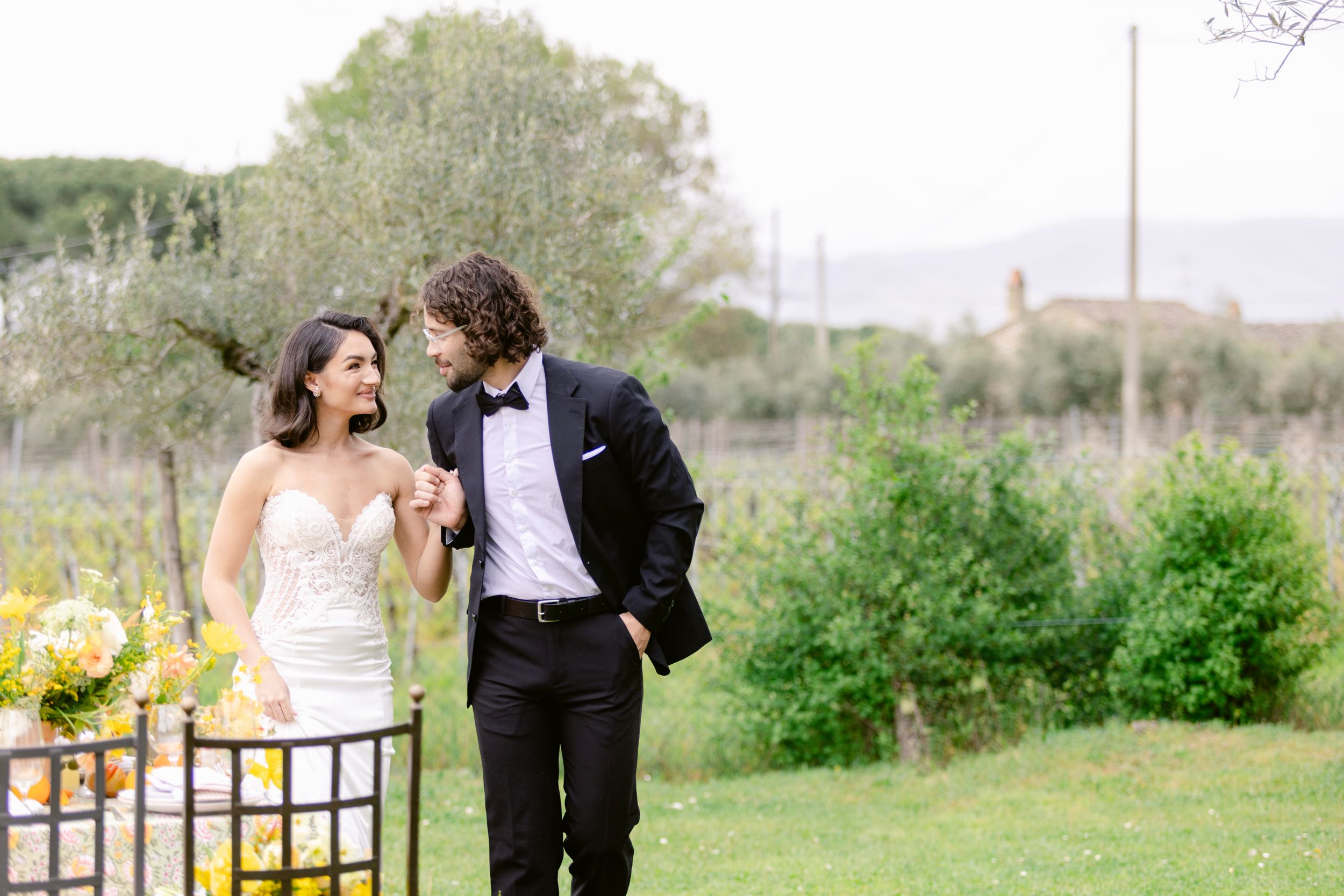 A couple in wedding attire walks through a lush garden setting during their romantic outdoor photo session.