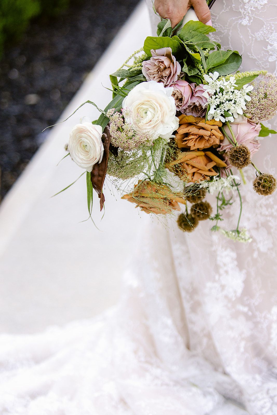 White roses and delicate florals cascade over white lace fabric in an elegant arrangement.