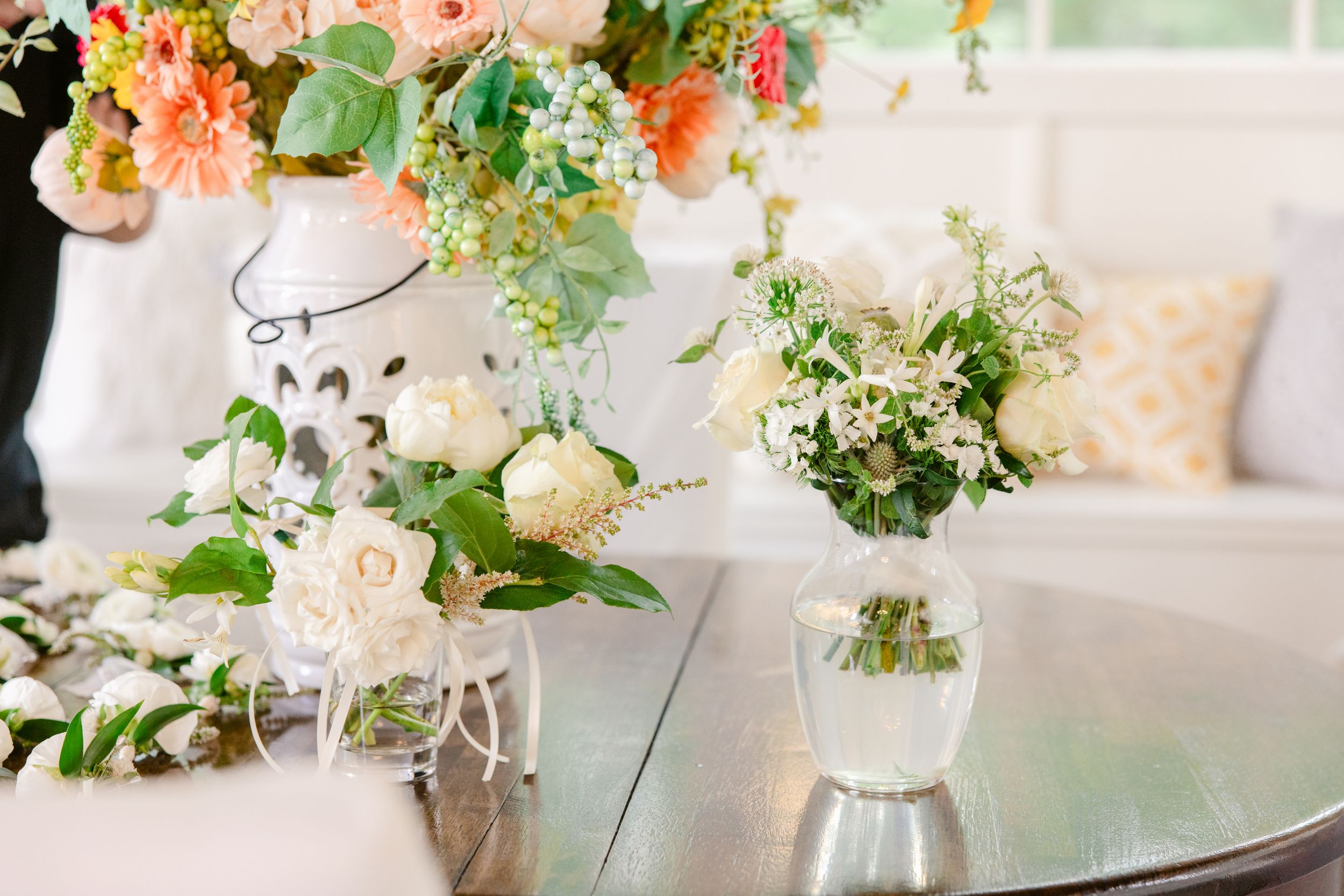 Elegant wedding table settings with blush pink floral centerpieces and crystal glassware in a light-filled reception space.