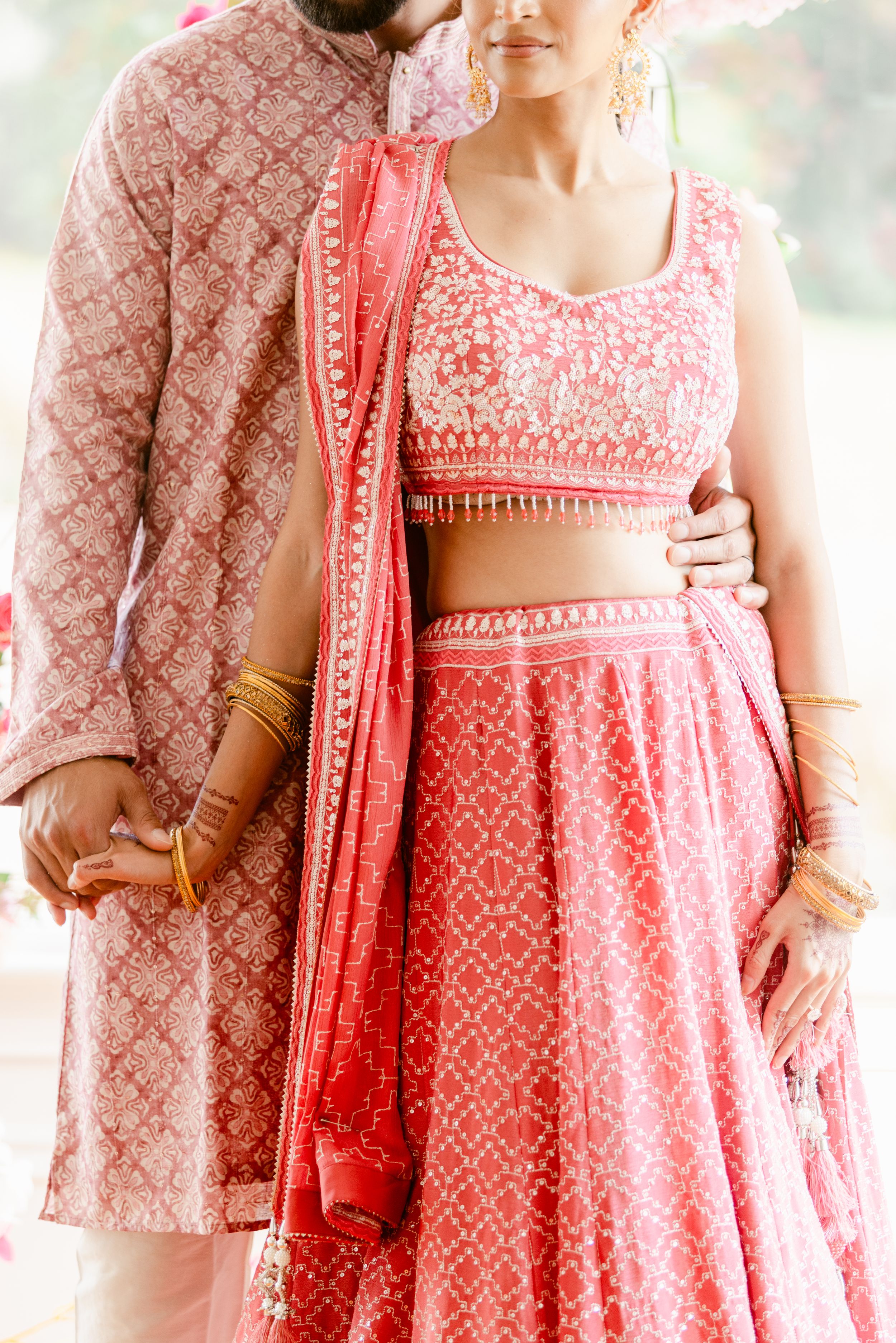Close-up of coral and pink patterned traditional Indian dresses with detailed embroidery.