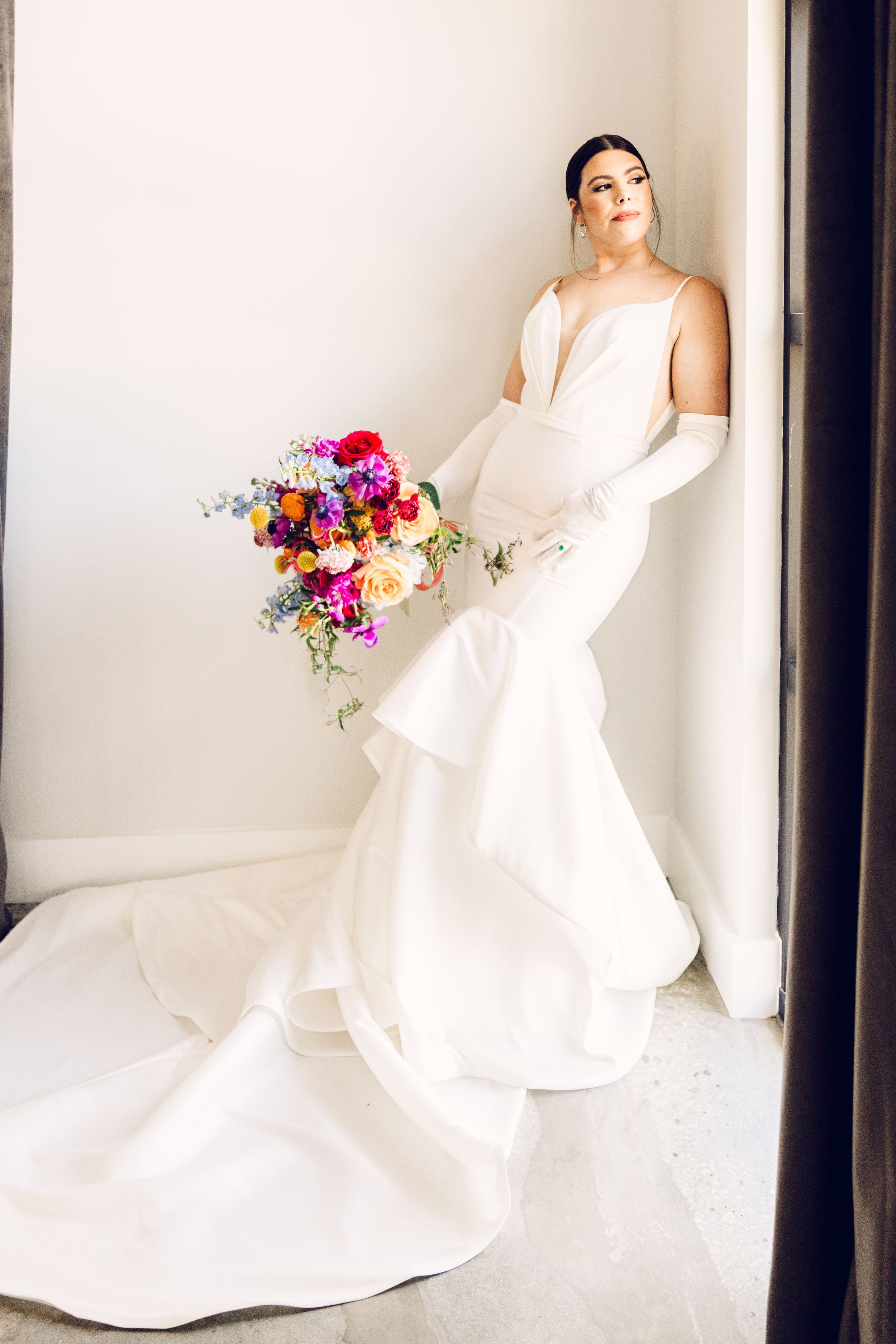 Bride in elegant white wedding gown poses with vibrant colorful bouquet against light backdrop in four sequential shots.