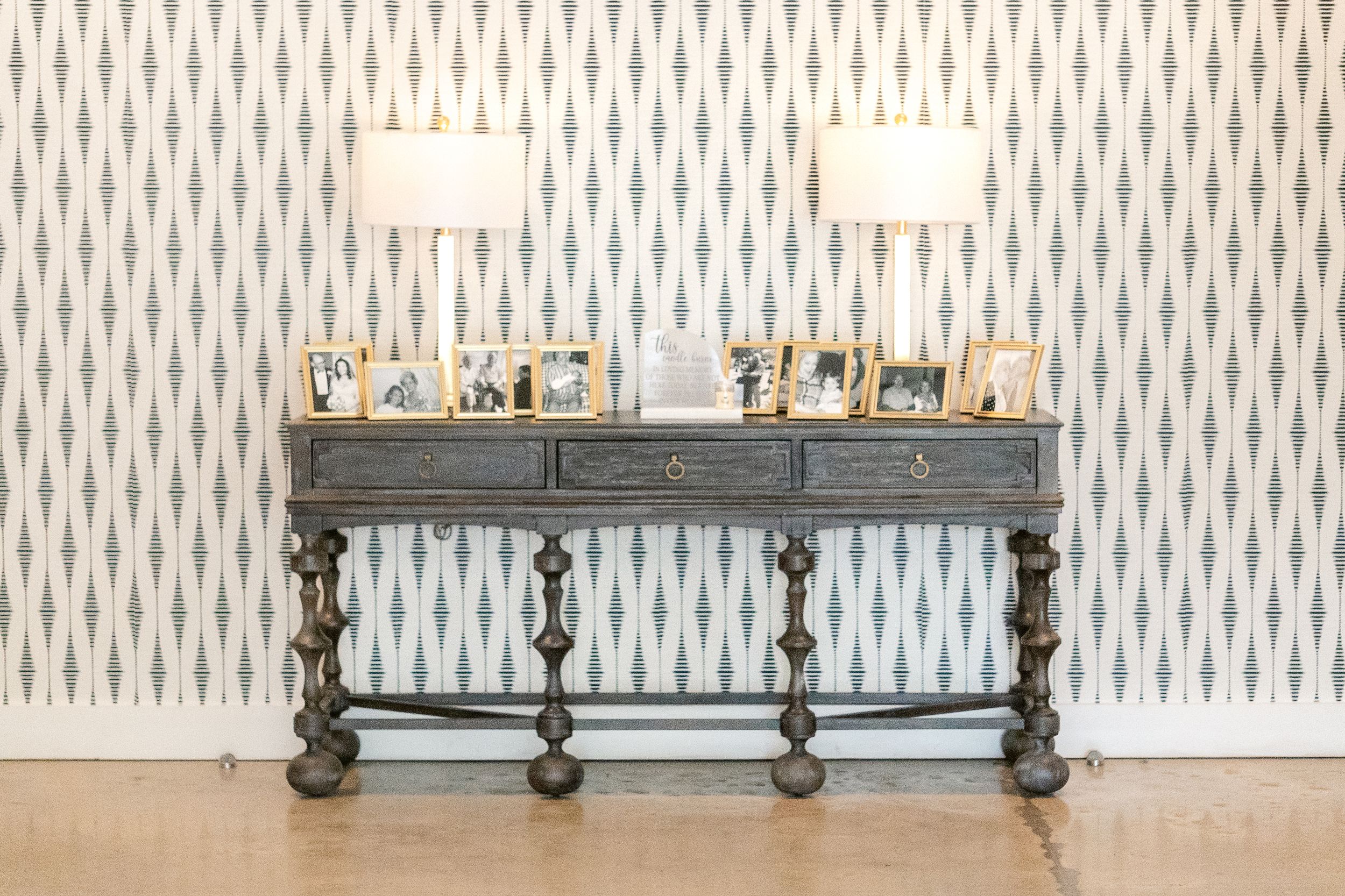 A modern interior design showroom displays elegant light fixtures and wallpaper with a geometric pattern.